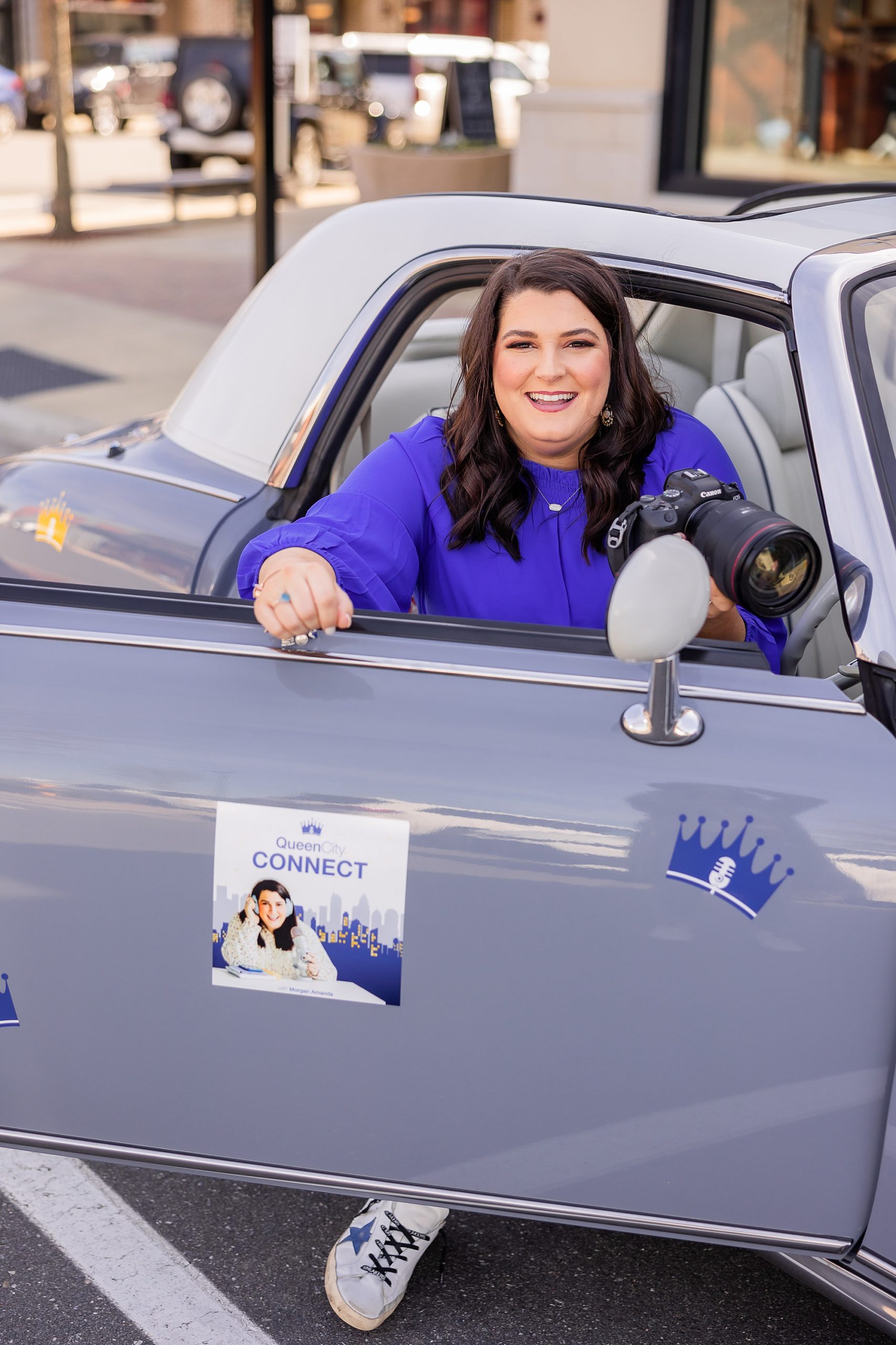 woman leans out of purple car with The Queen City Connect Podcast logo