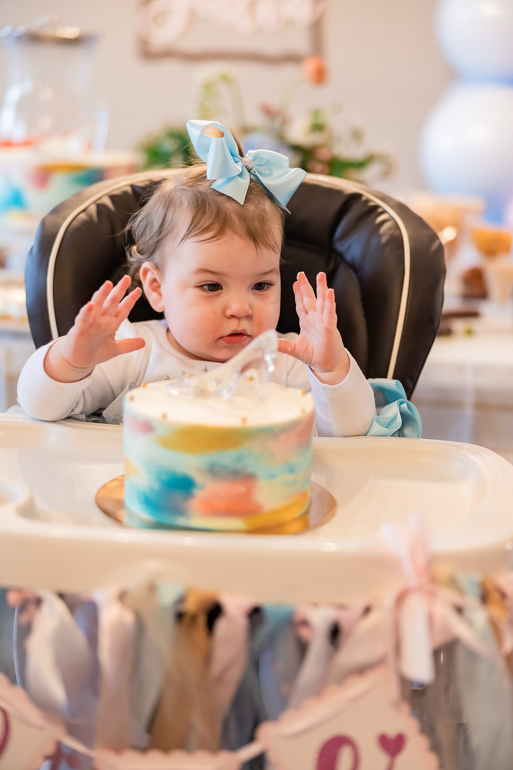 toddler plays with cake during Princess themed first birthday party
