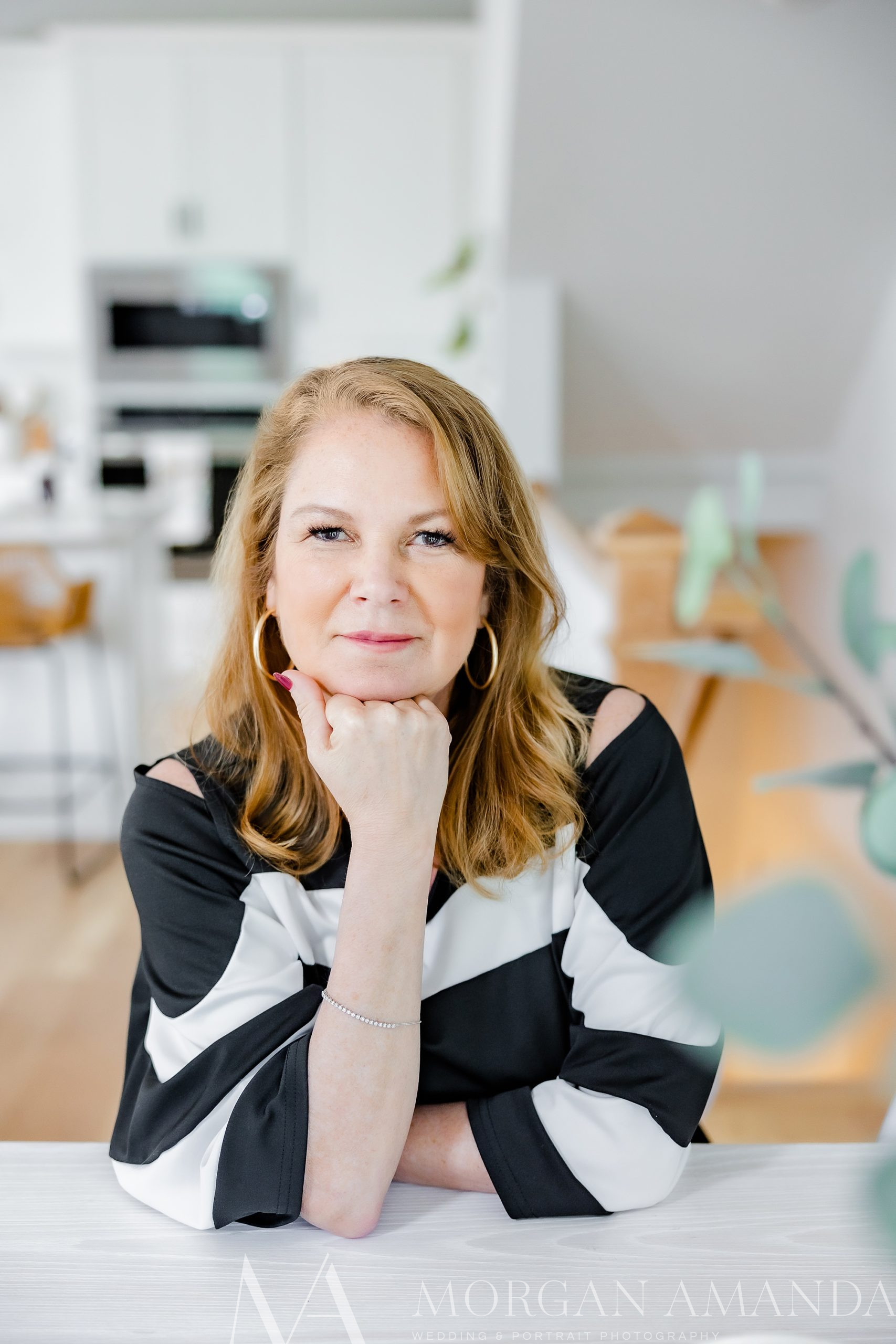 woman leans on kitchen table during  branding session for real estate agent