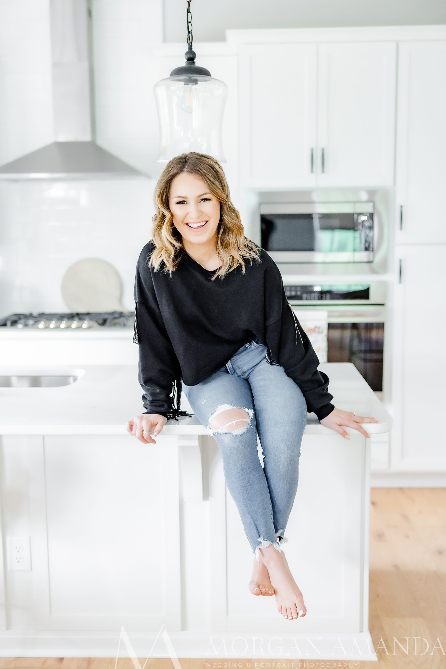 woman sits on kitchen counter during  branding session for real estate agent