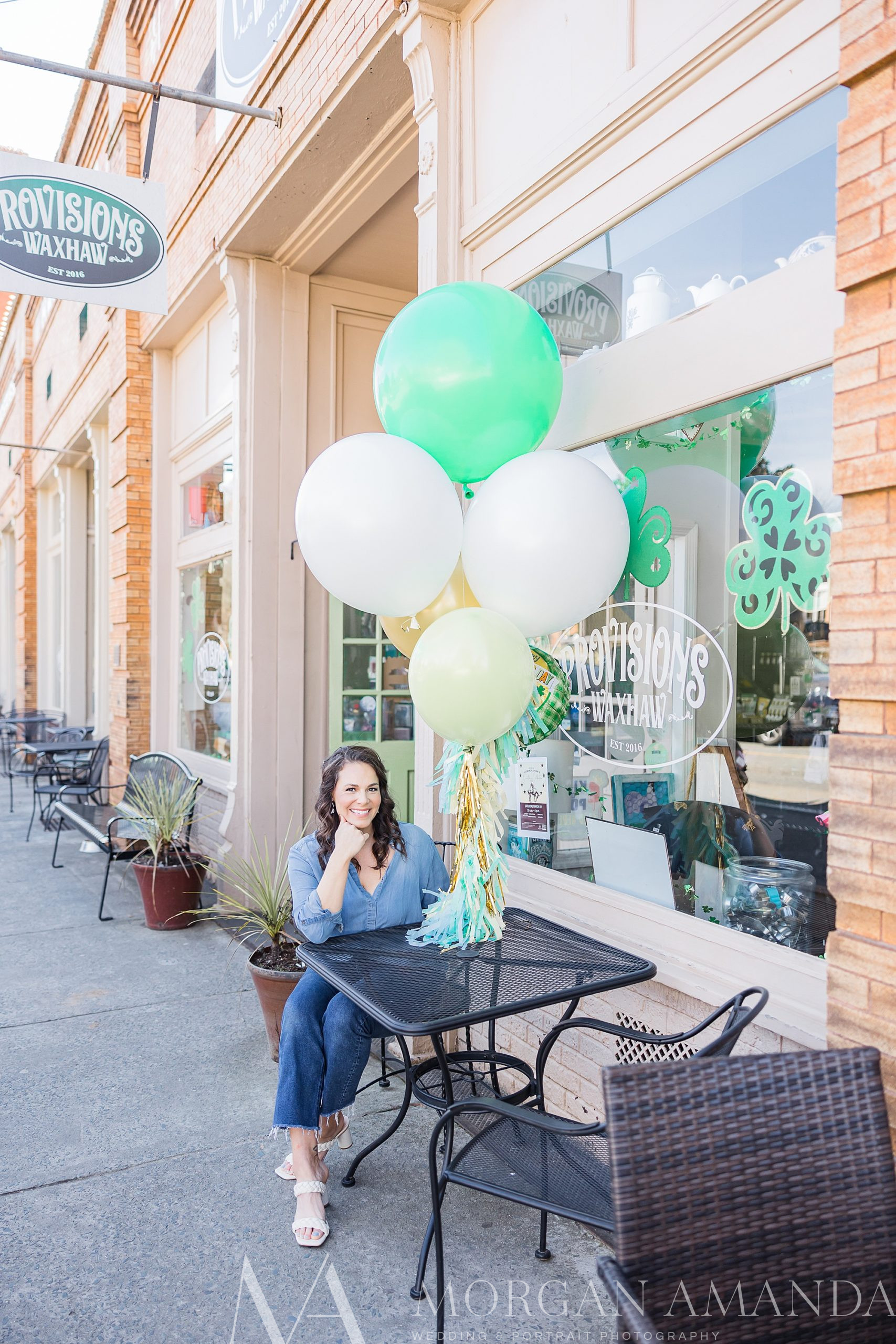woman sits by green and white balloons