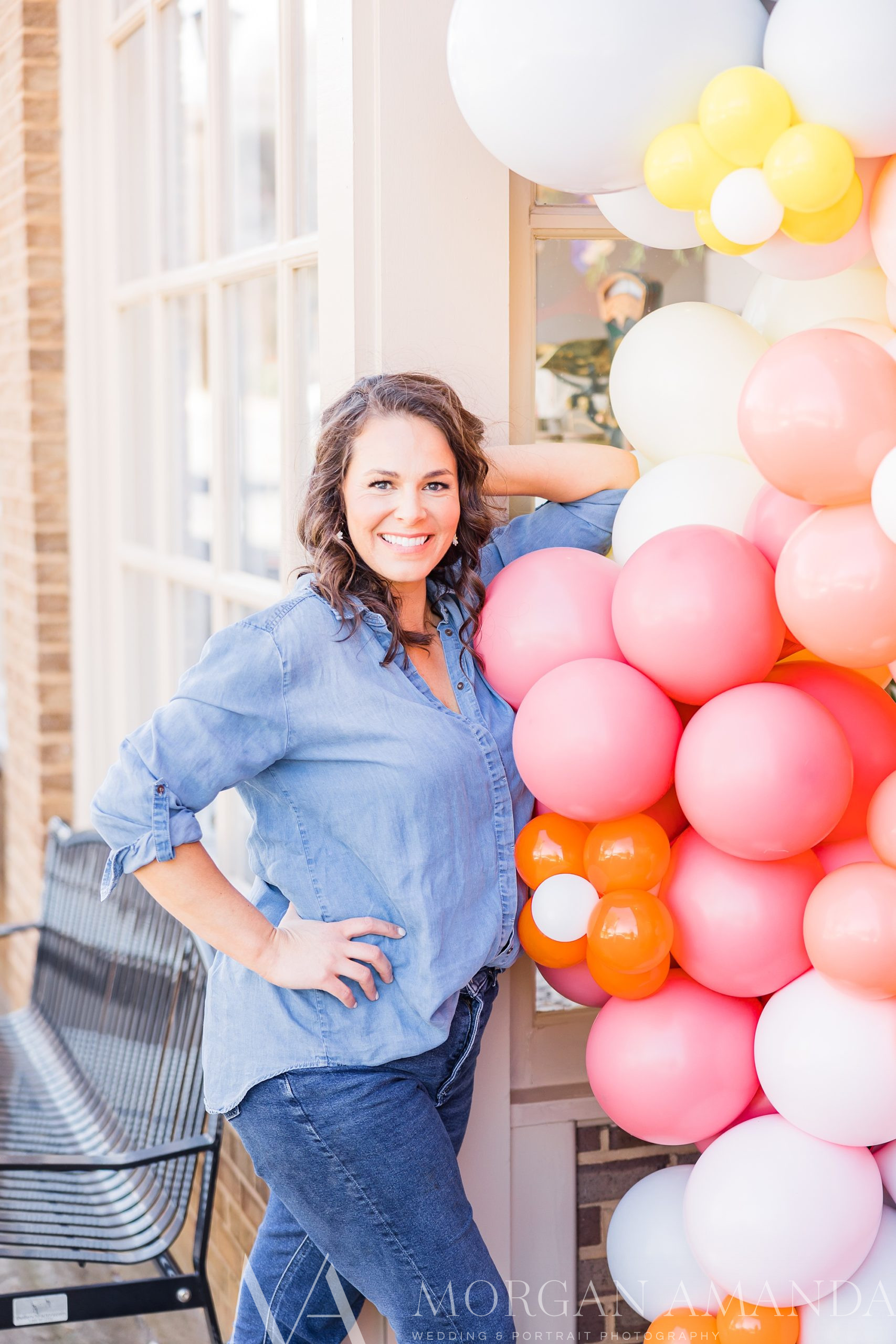 woman leans against balloon arch at shop door