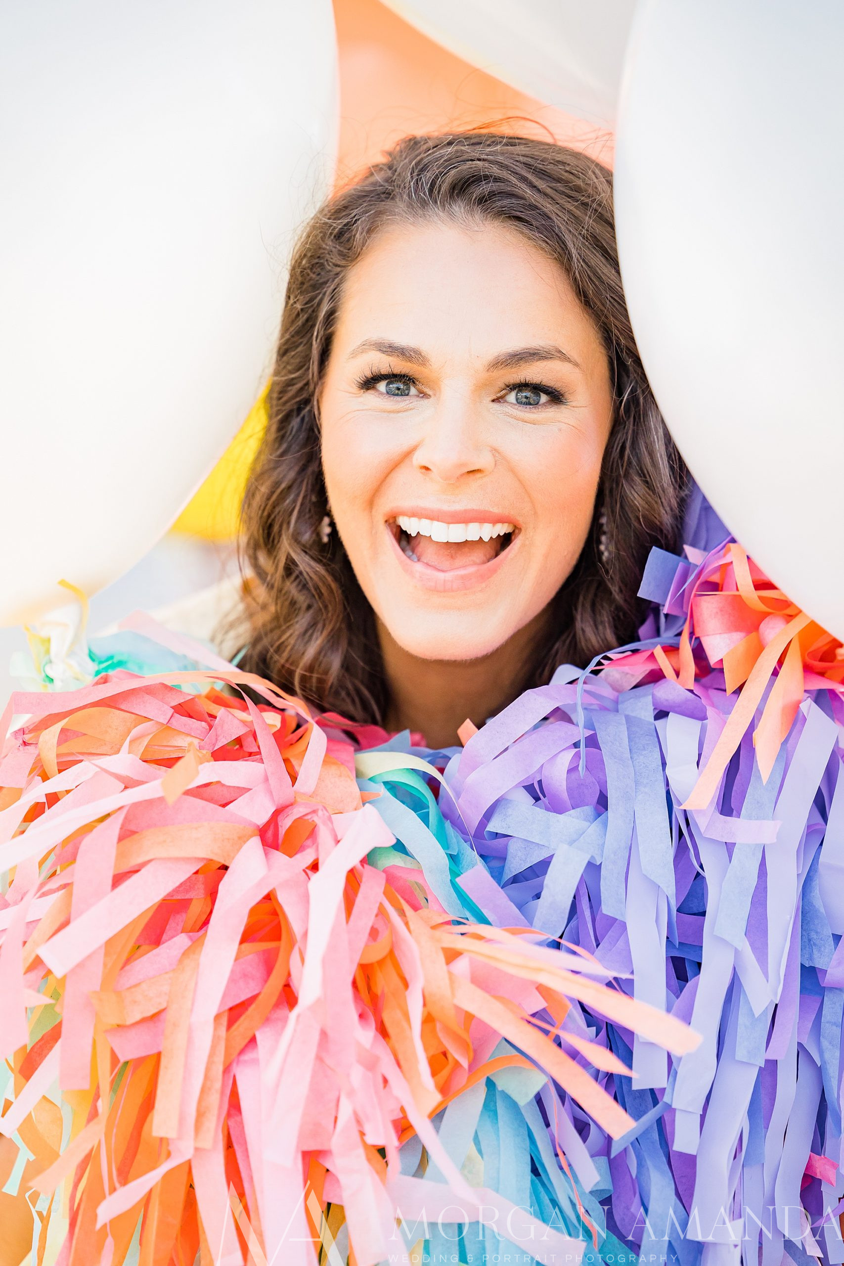 business owner pops her head out between white balloons during branding photos
