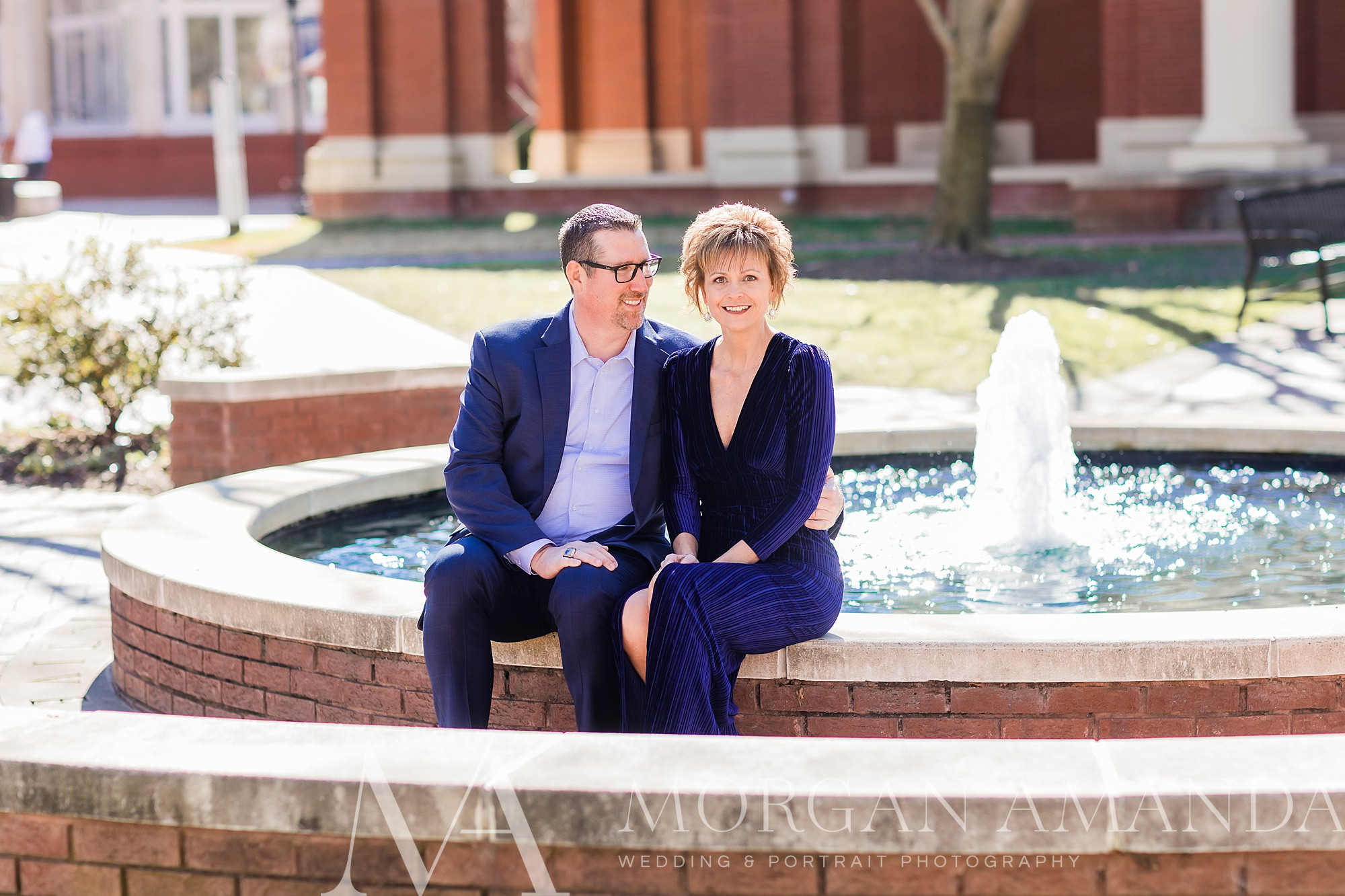 engaged couple sit by fountain at Queens University