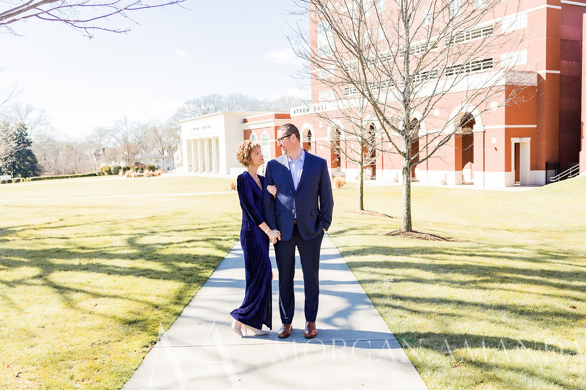 couple poses on sidewalk at Queens University