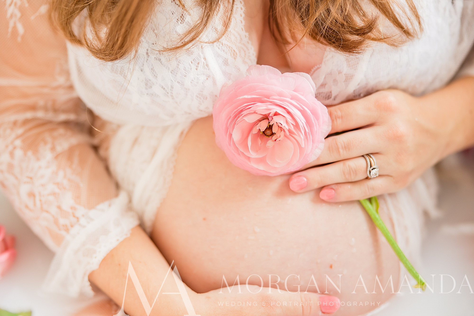mom holds pink rose by tummy during maternity photos in tub