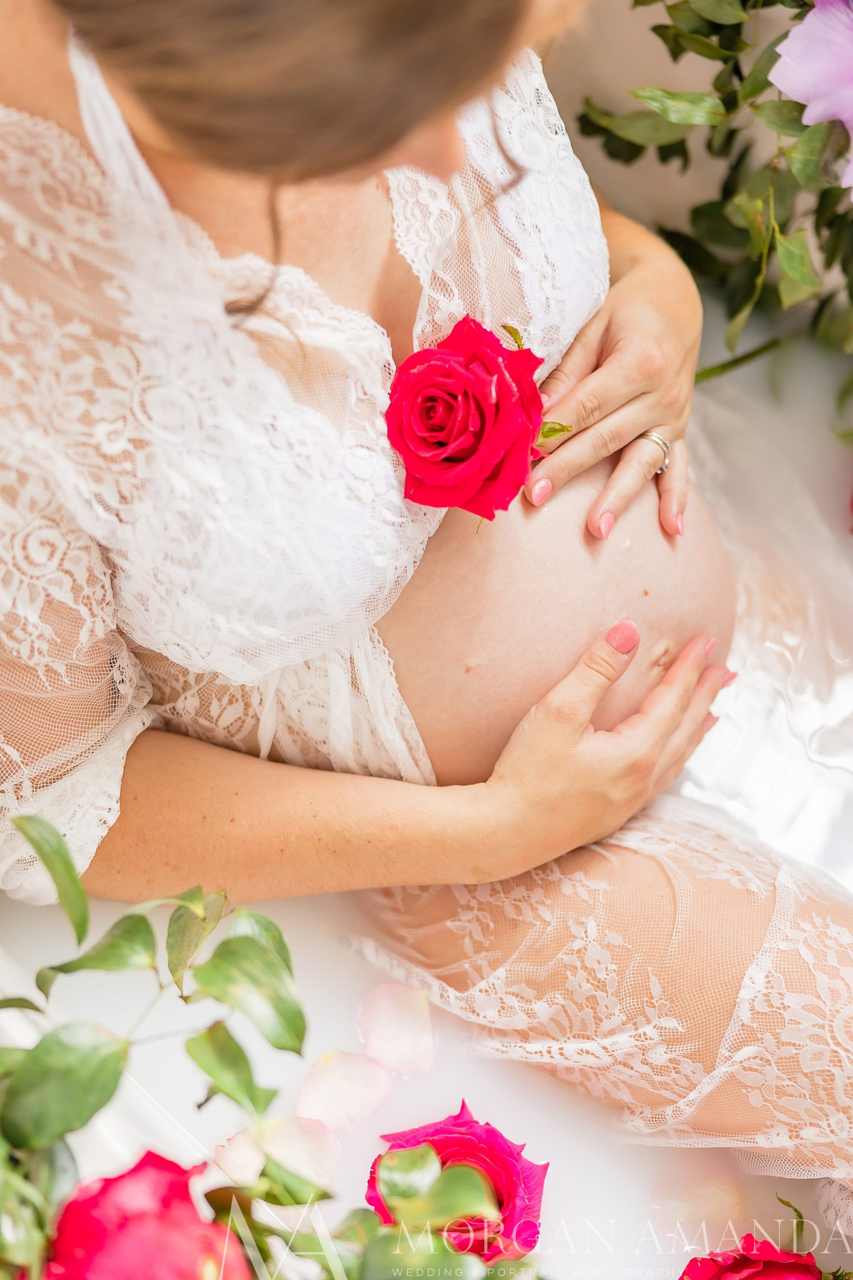 expecting mother holds flower to belly during milk bath maternity portraits