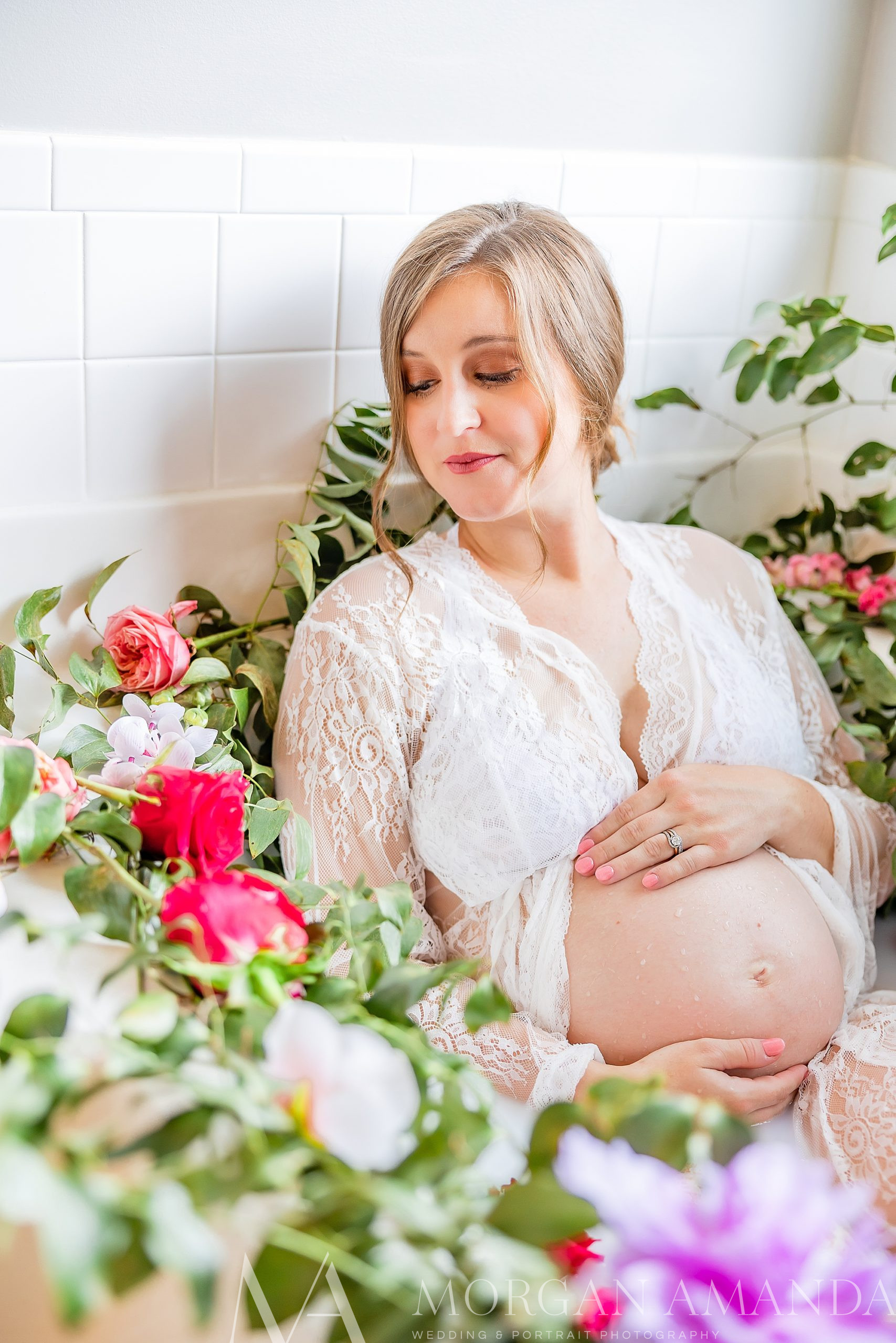 woman leans against bathroom wall during milk bath maternity portraits