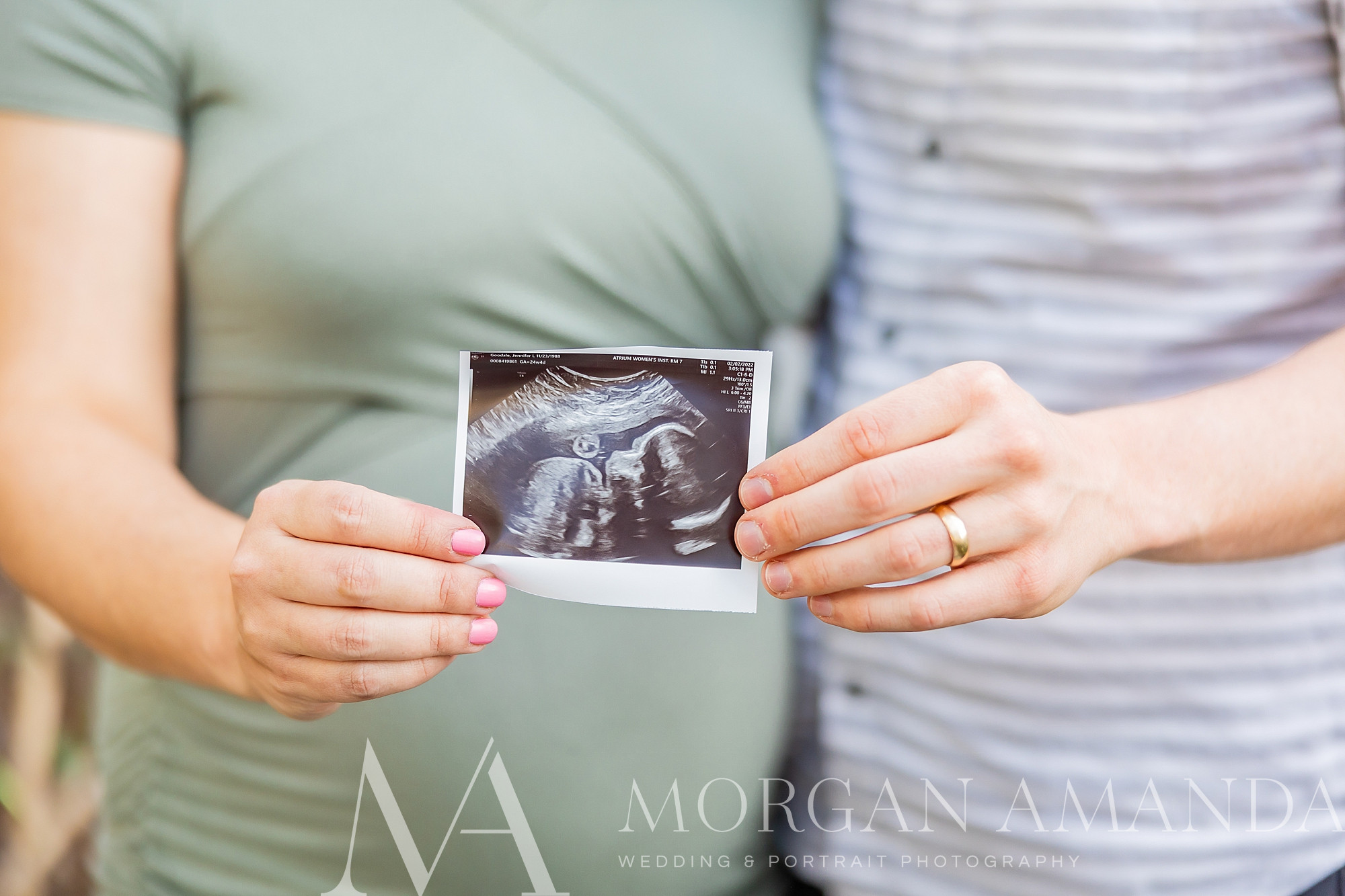 expecting parents hold sonogram together by mom's bump 