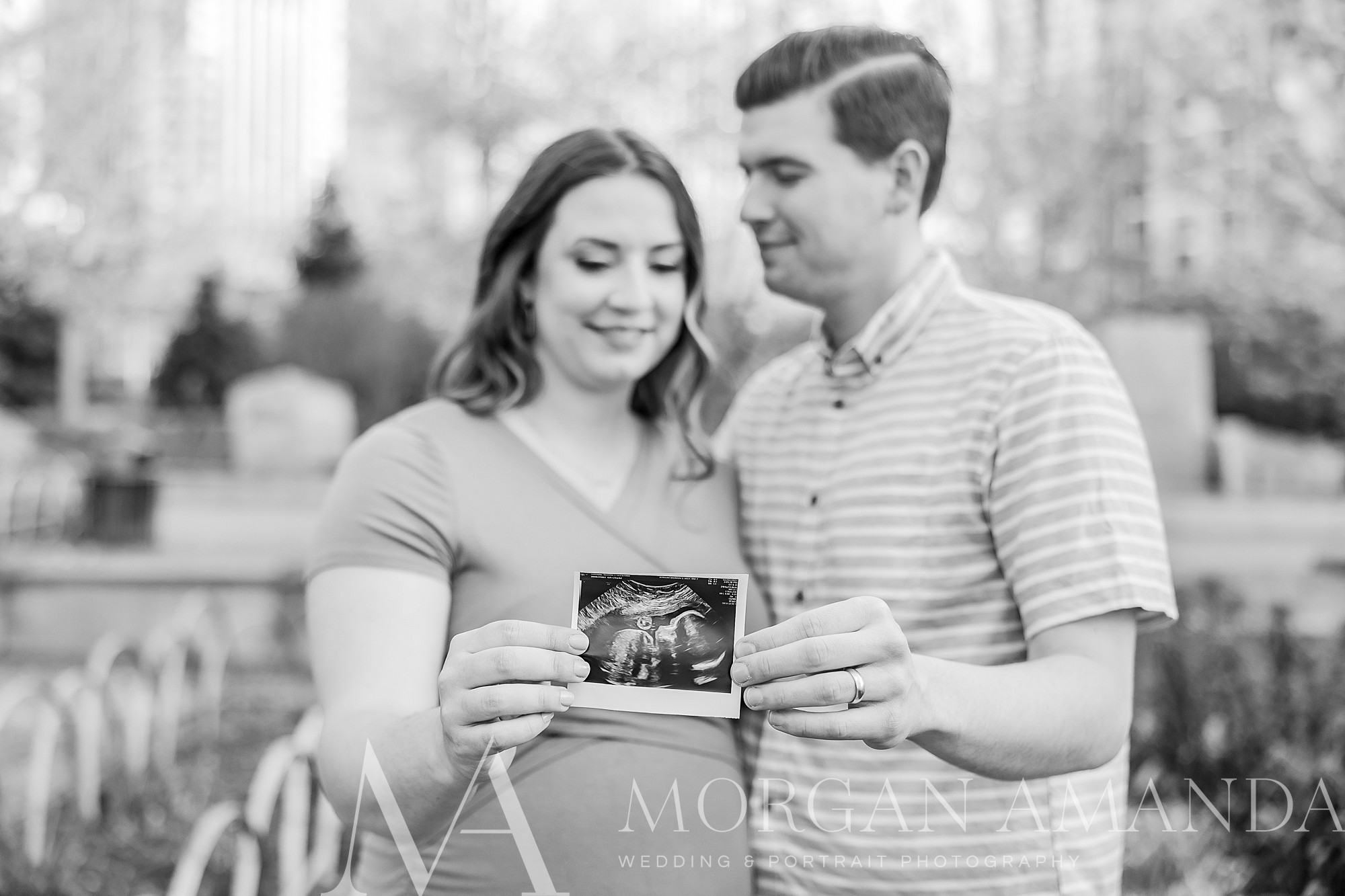 parents-to-be hold sonogram during maternity session in Uptown Charlotte 