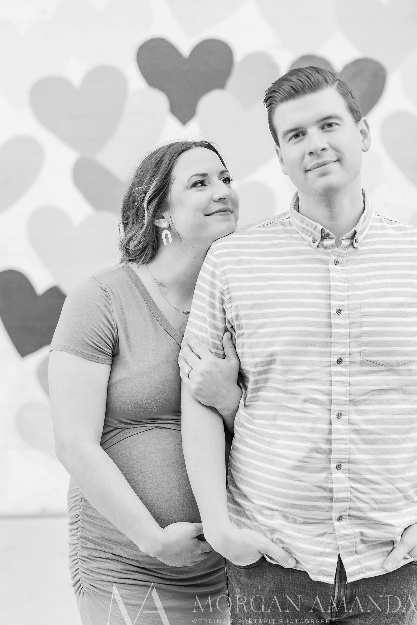 woman holds man's arm and belly during maternity photos
