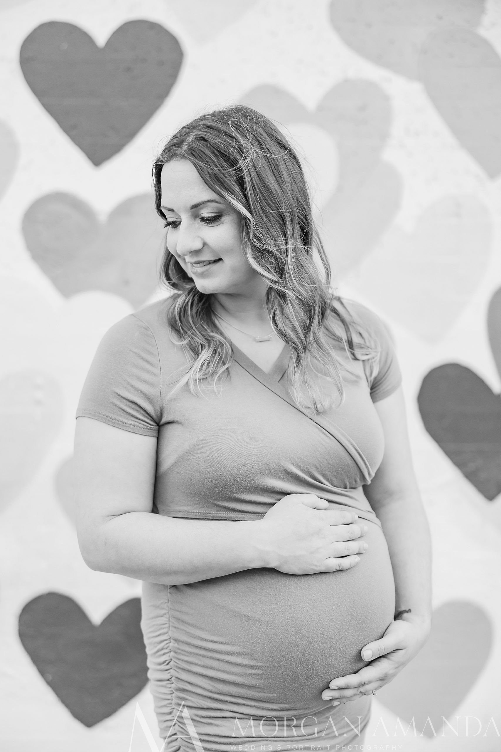 woman holds belly in wrap dress during Uptown Charlotte maternity photos