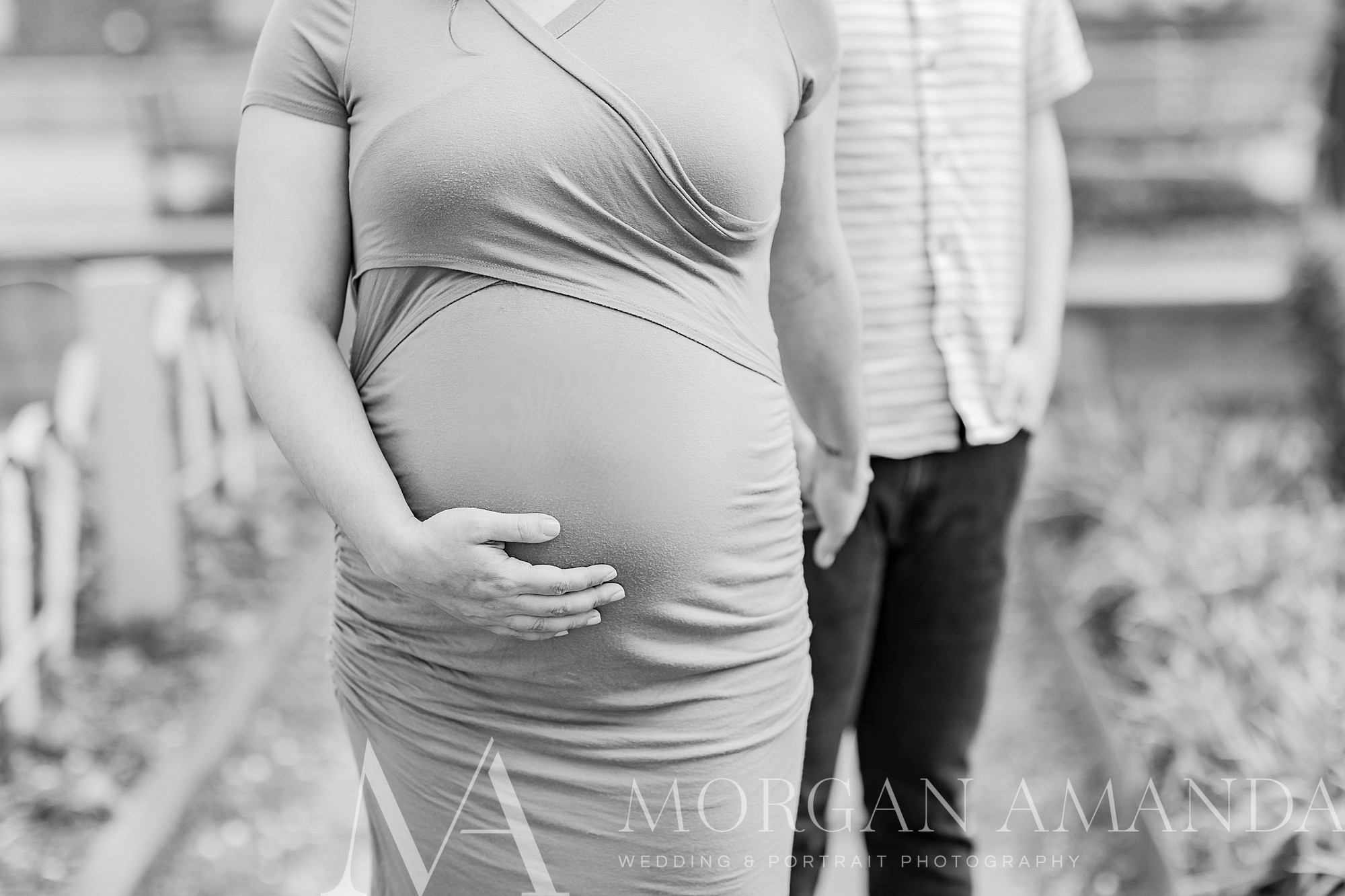 woman holds husband's hand while holding baby bump