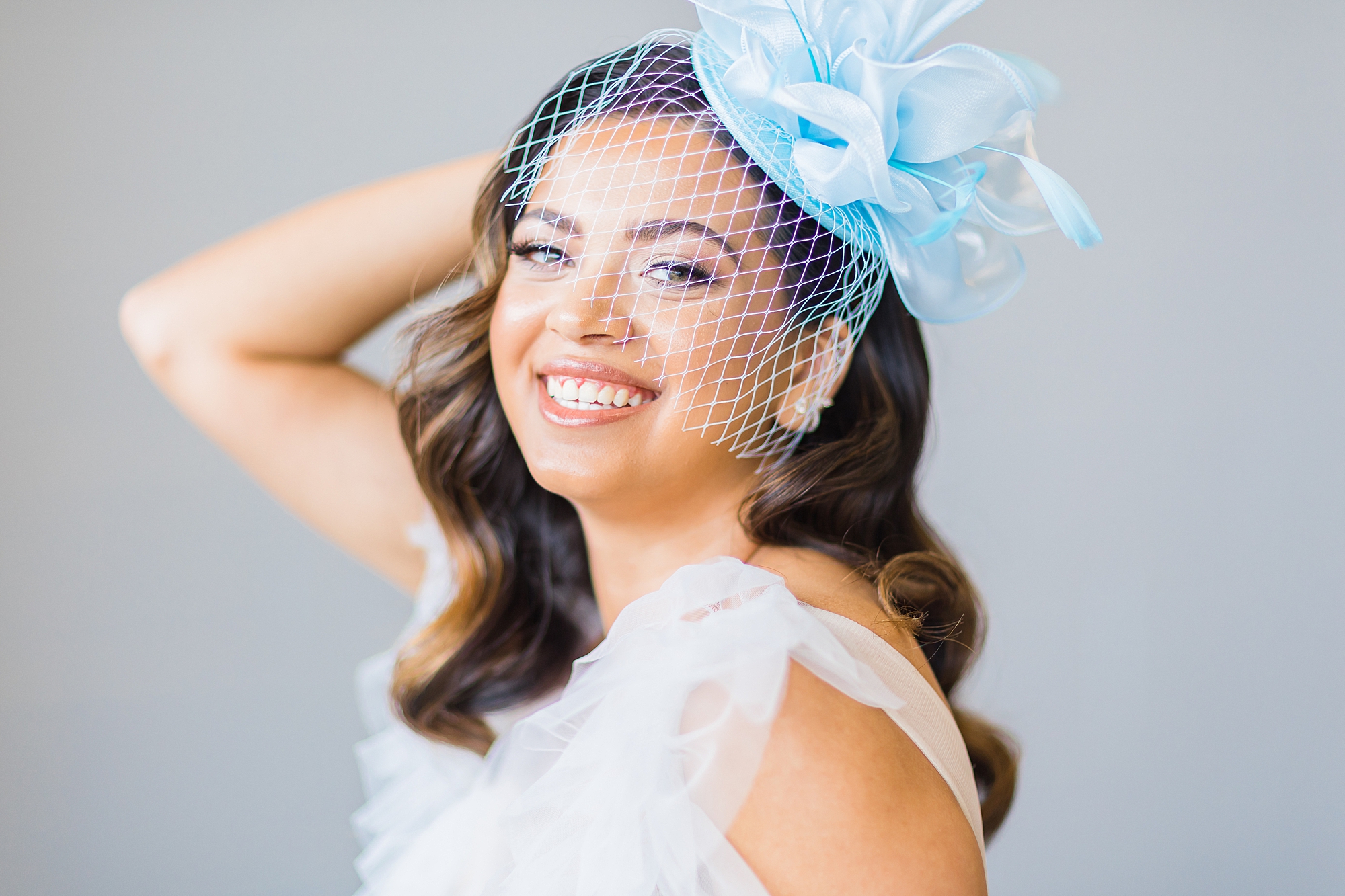 bride stands with blue birdcage on head