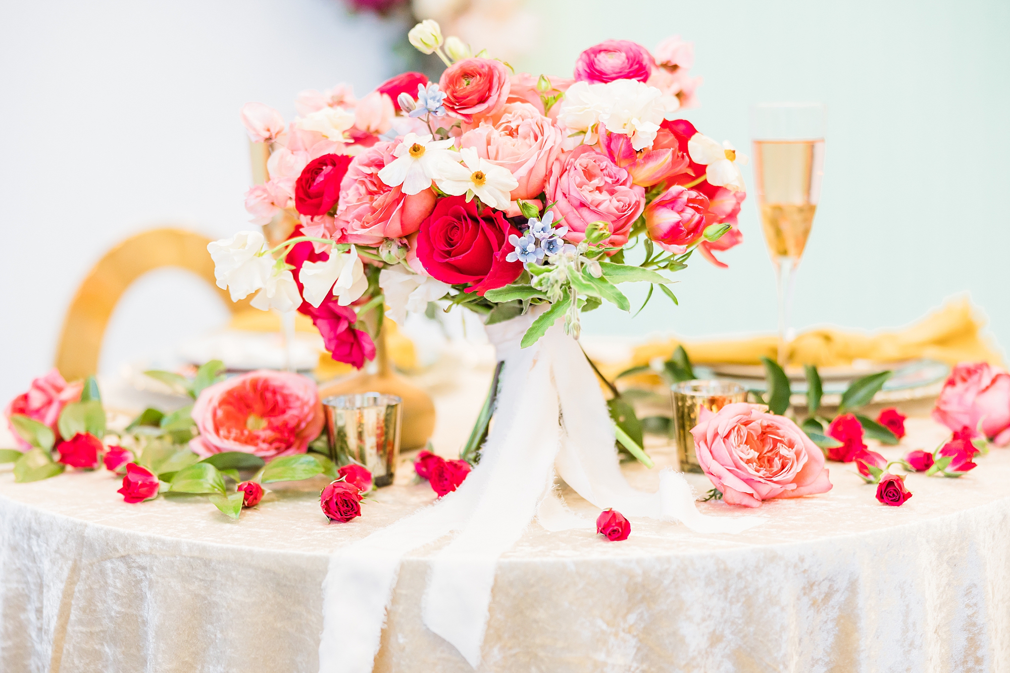 pink and red floral display on sweetheart table with gold accents 