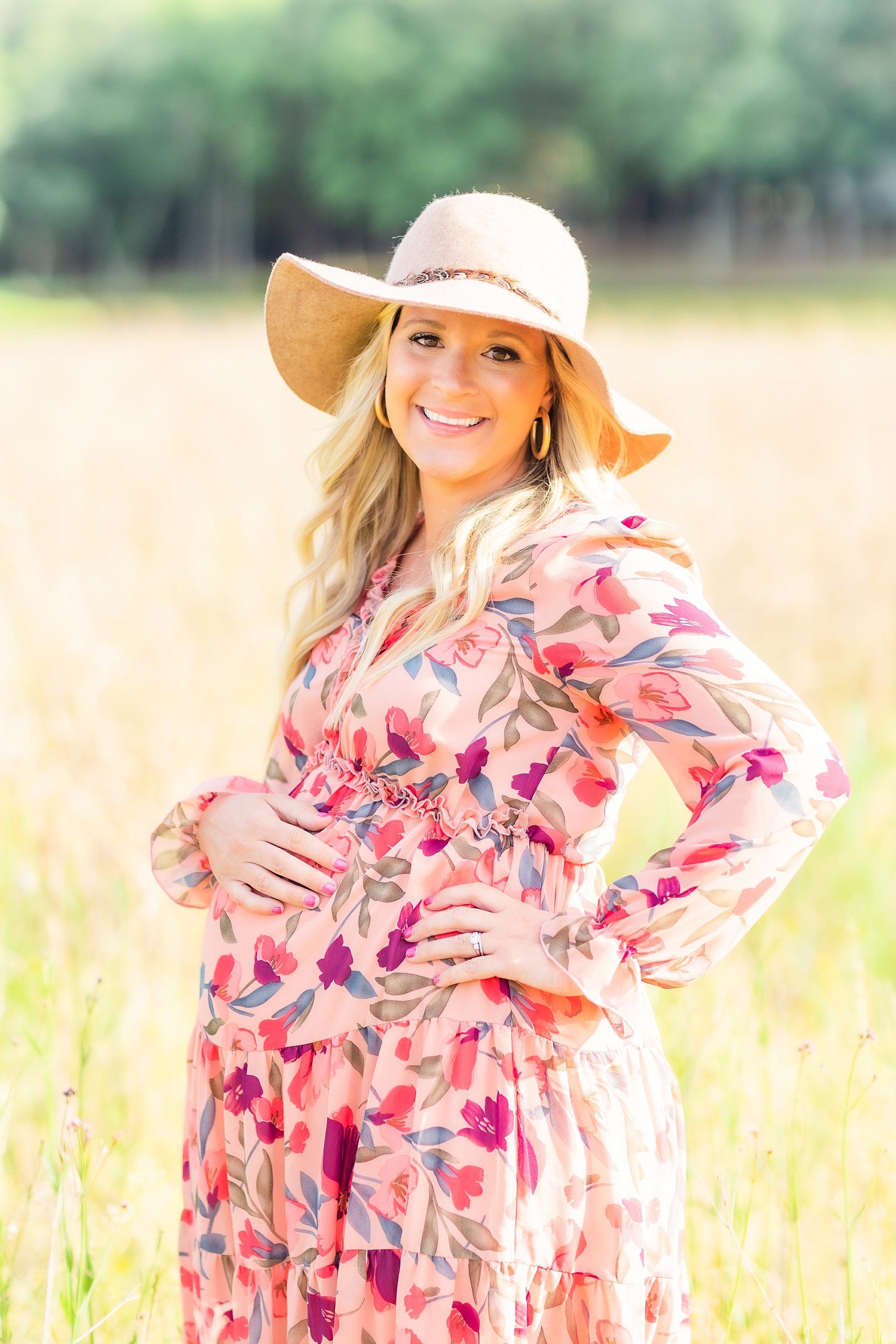 mom in big floppy hat holds bump during maternity photos