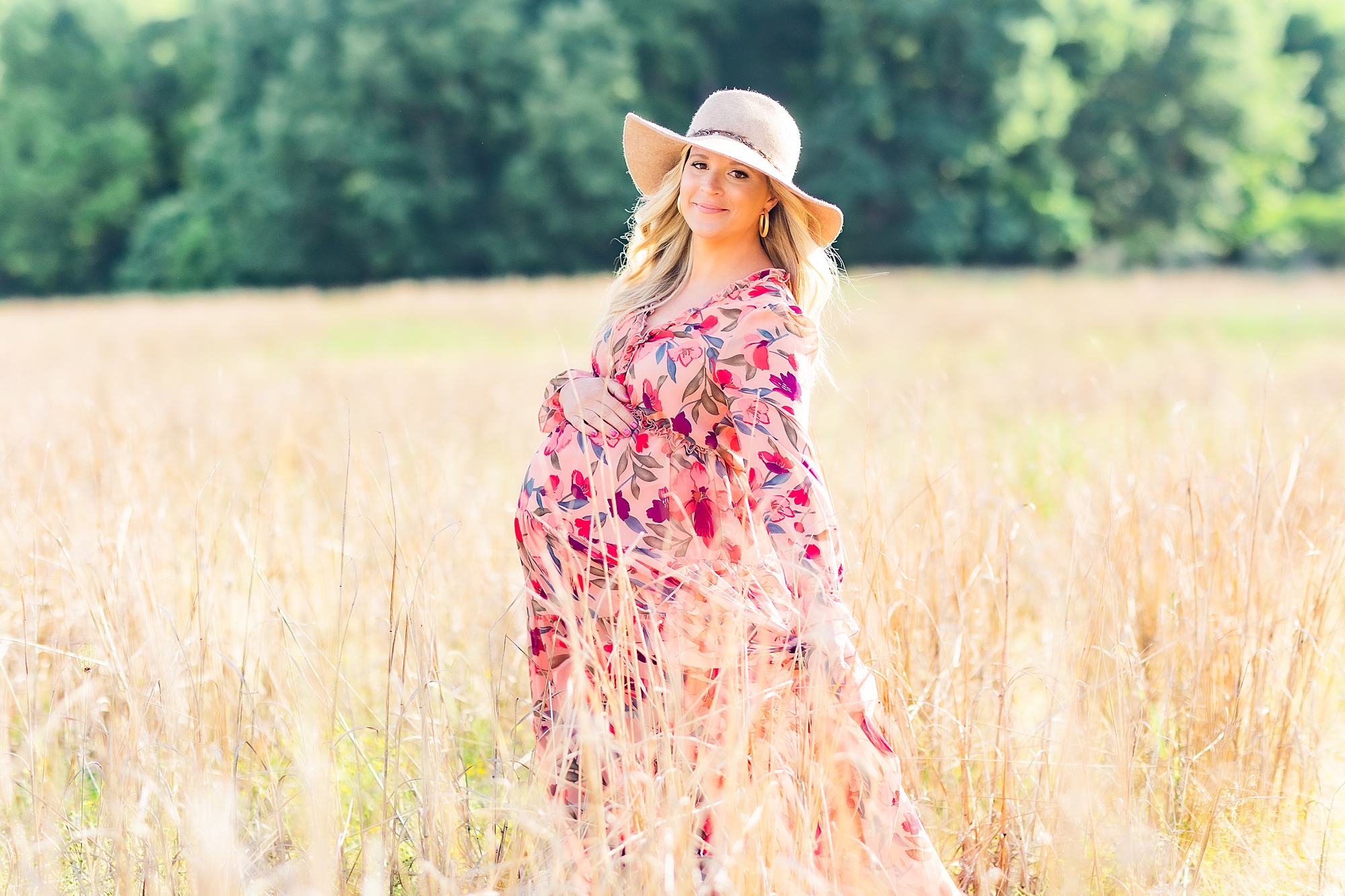 mom stands in field during maternity photos holding baby bump