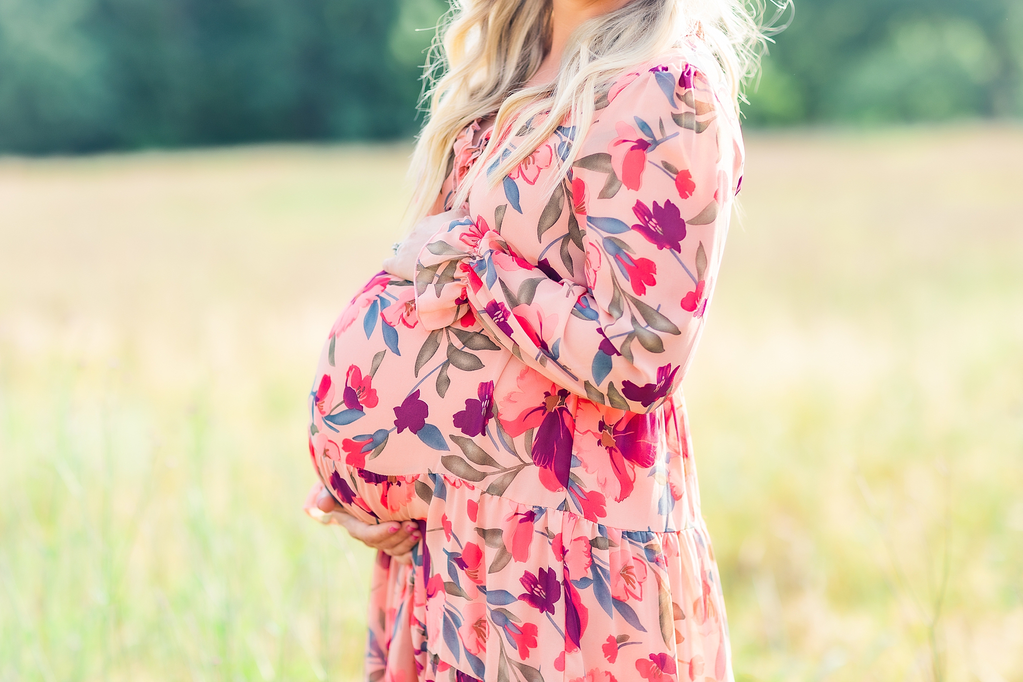 mom-to-be holds baby bump in pink floral dress
