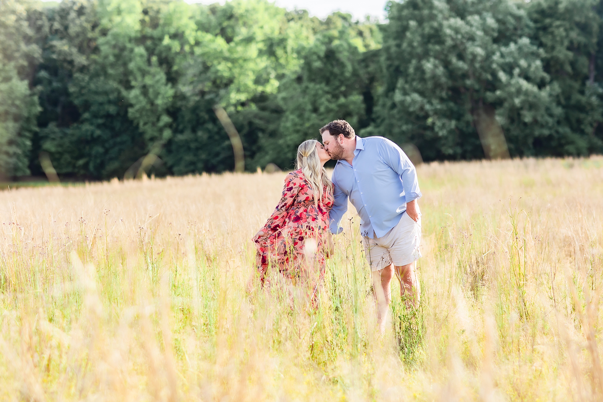 new parents kiss in field during maternity photos