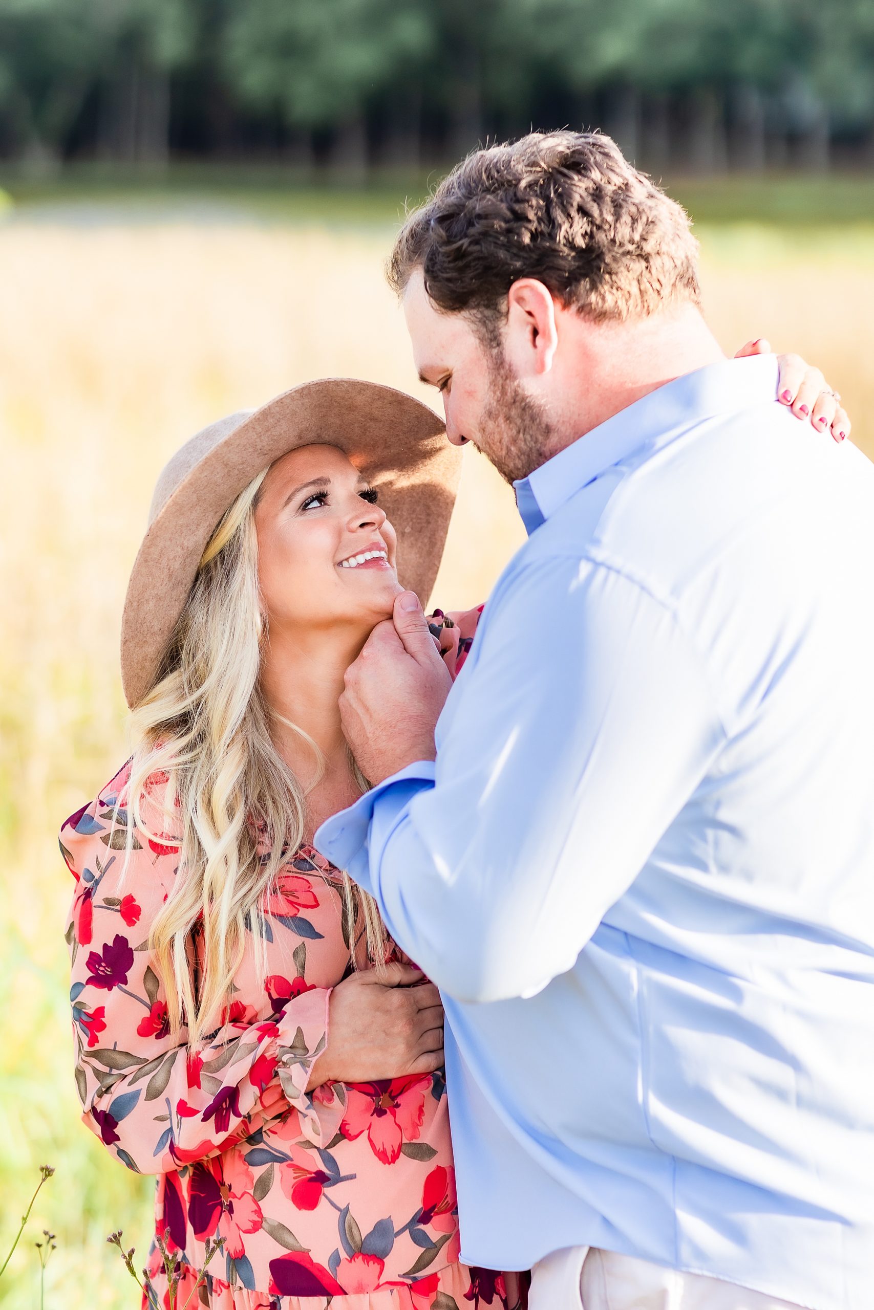 husband and wife look at each other in field during maternity photos