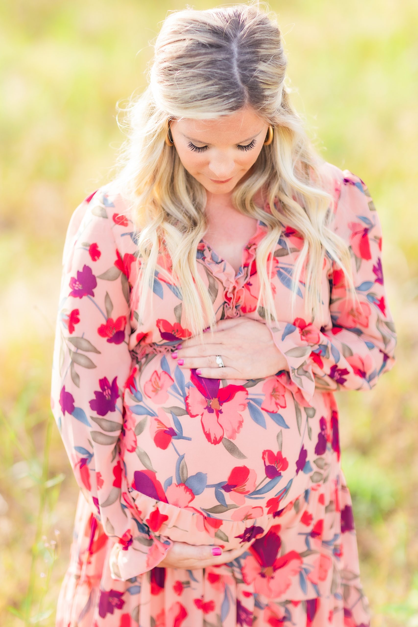 mother stands in Charlotte field during maternity portraits 