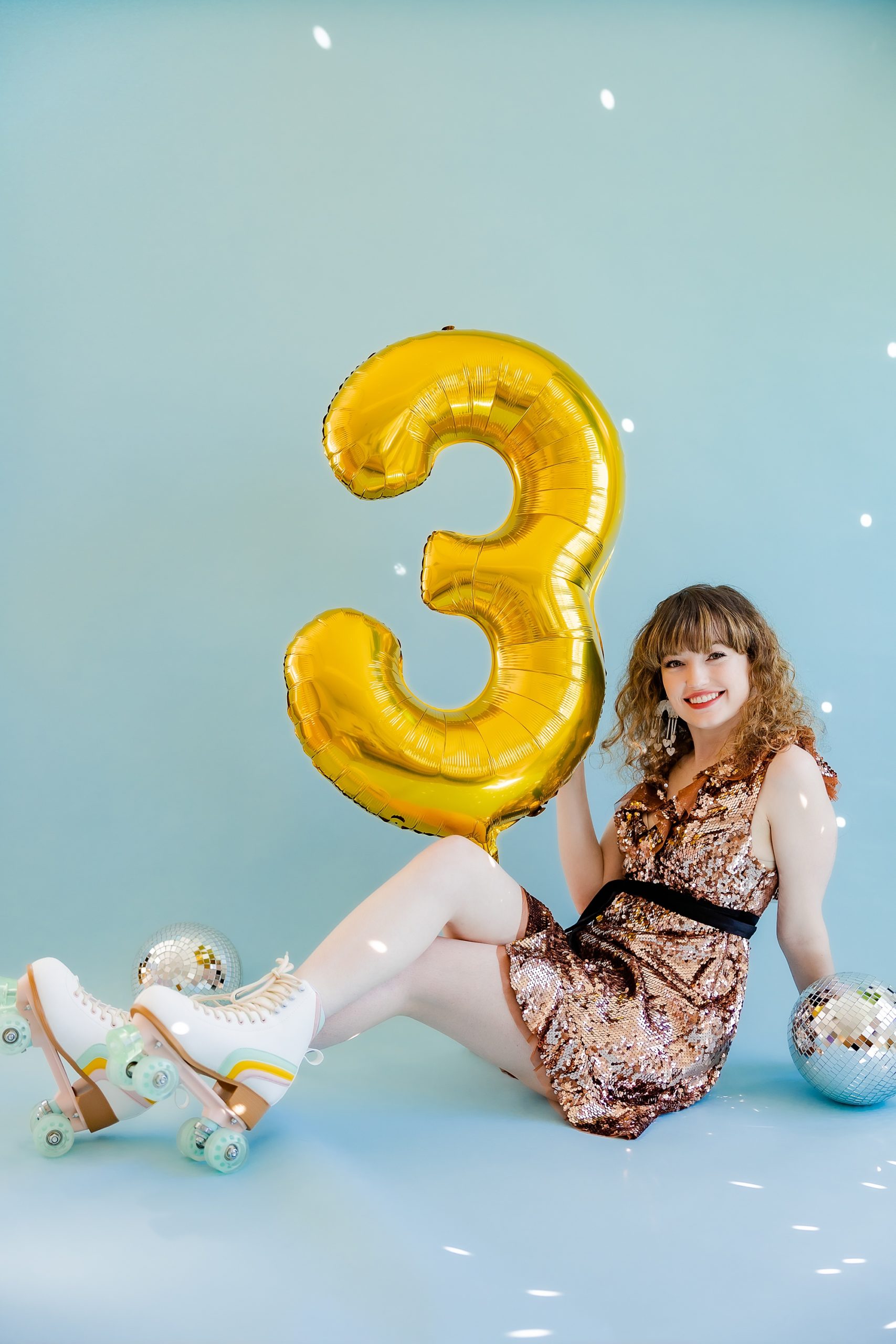 business owner sits in sparkly dress with roller skates during playful branding portraits