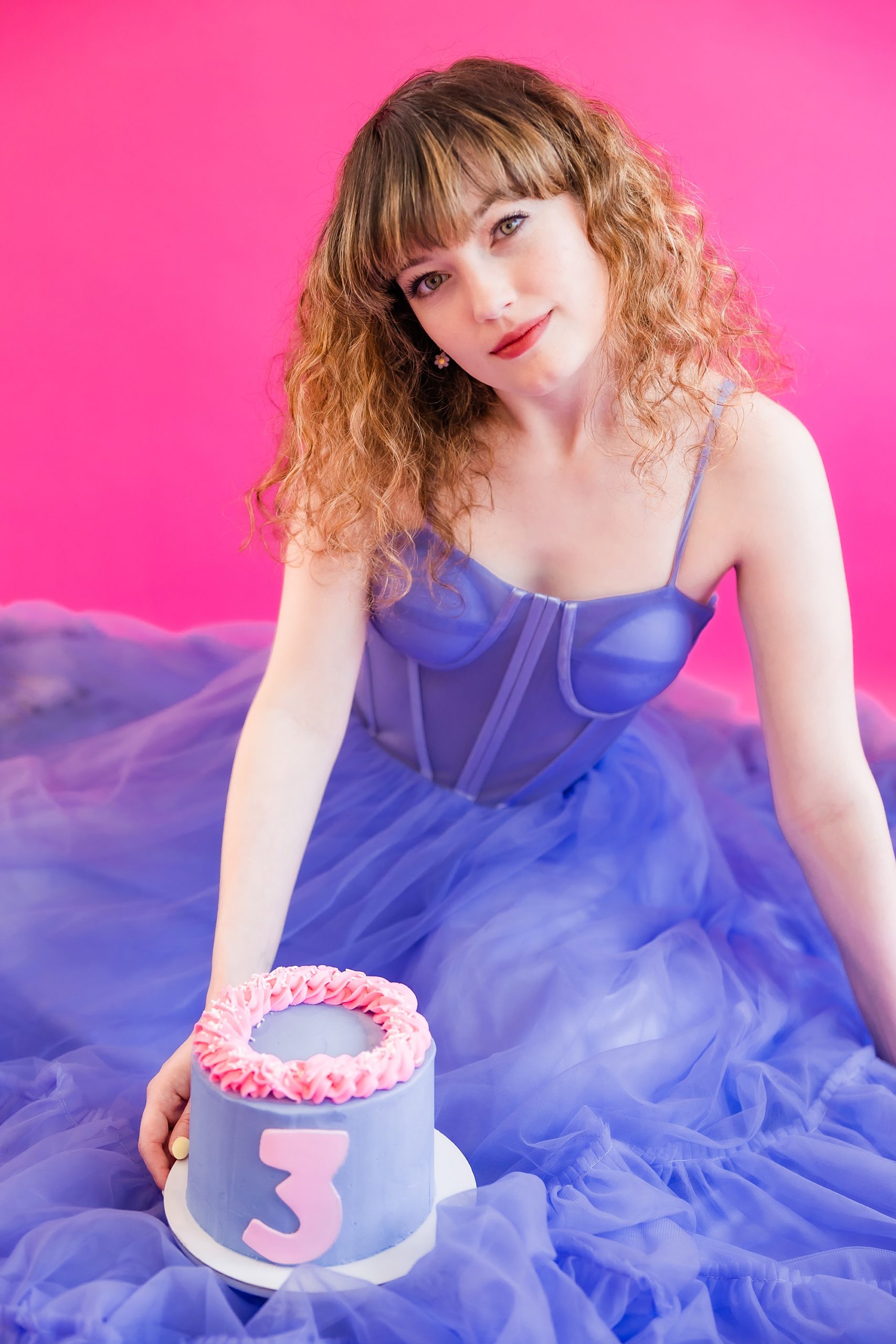 woman sits with purple and pink cake during playful branding portraits