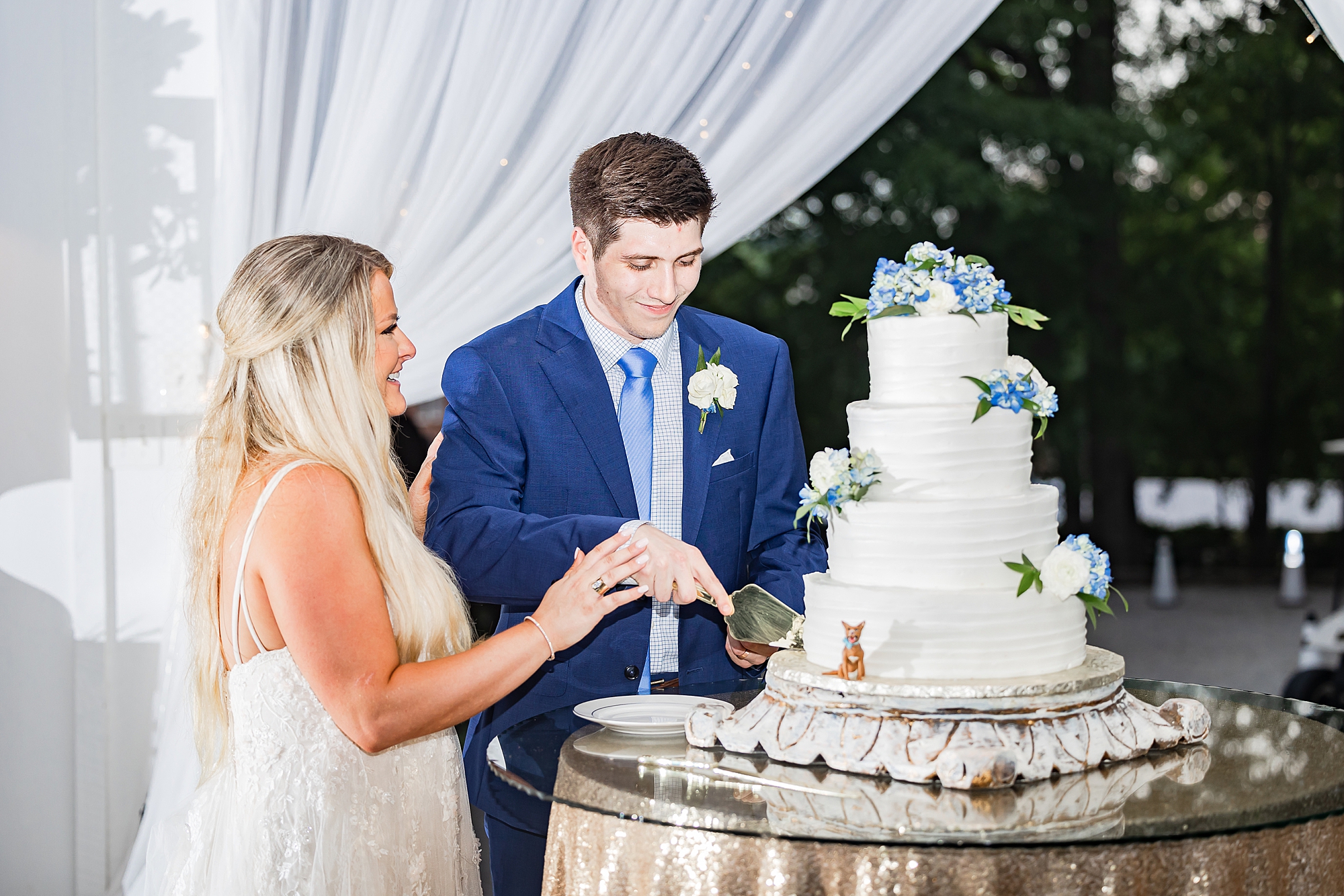 newlyweds cut wedding cake during Vintage White Barn wedding reception