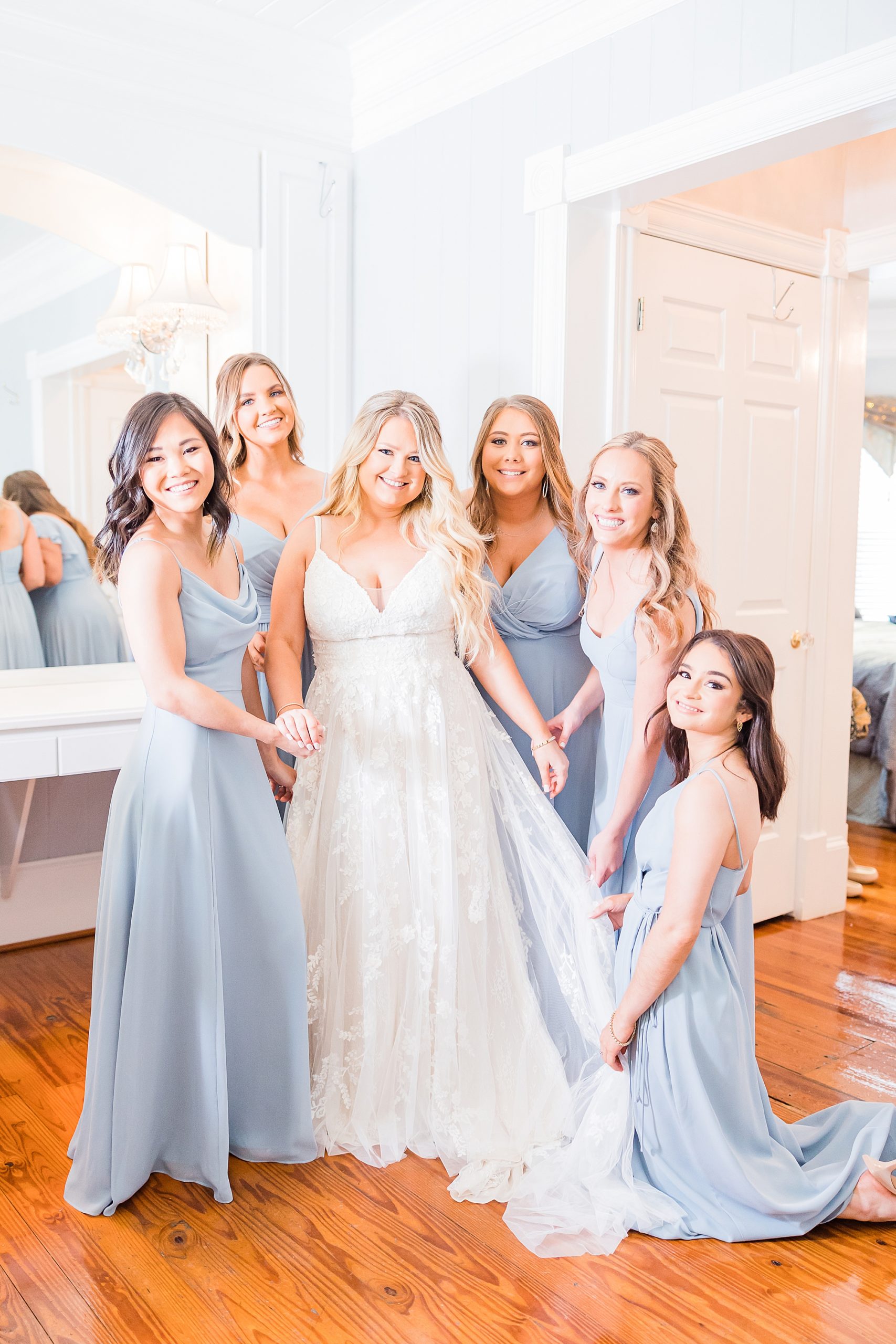 bride stands with bridesmaids in blue gowns