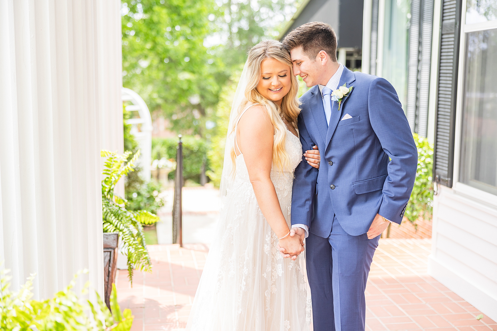 groom leans into bride's cheek during portraits on the veranda at Victoria Belle Mansion