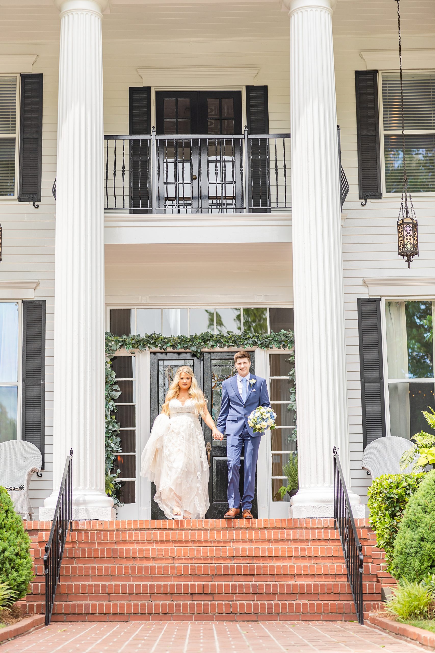 bride and groom hold hands walking down the steps at Victoria Belle Mansion
