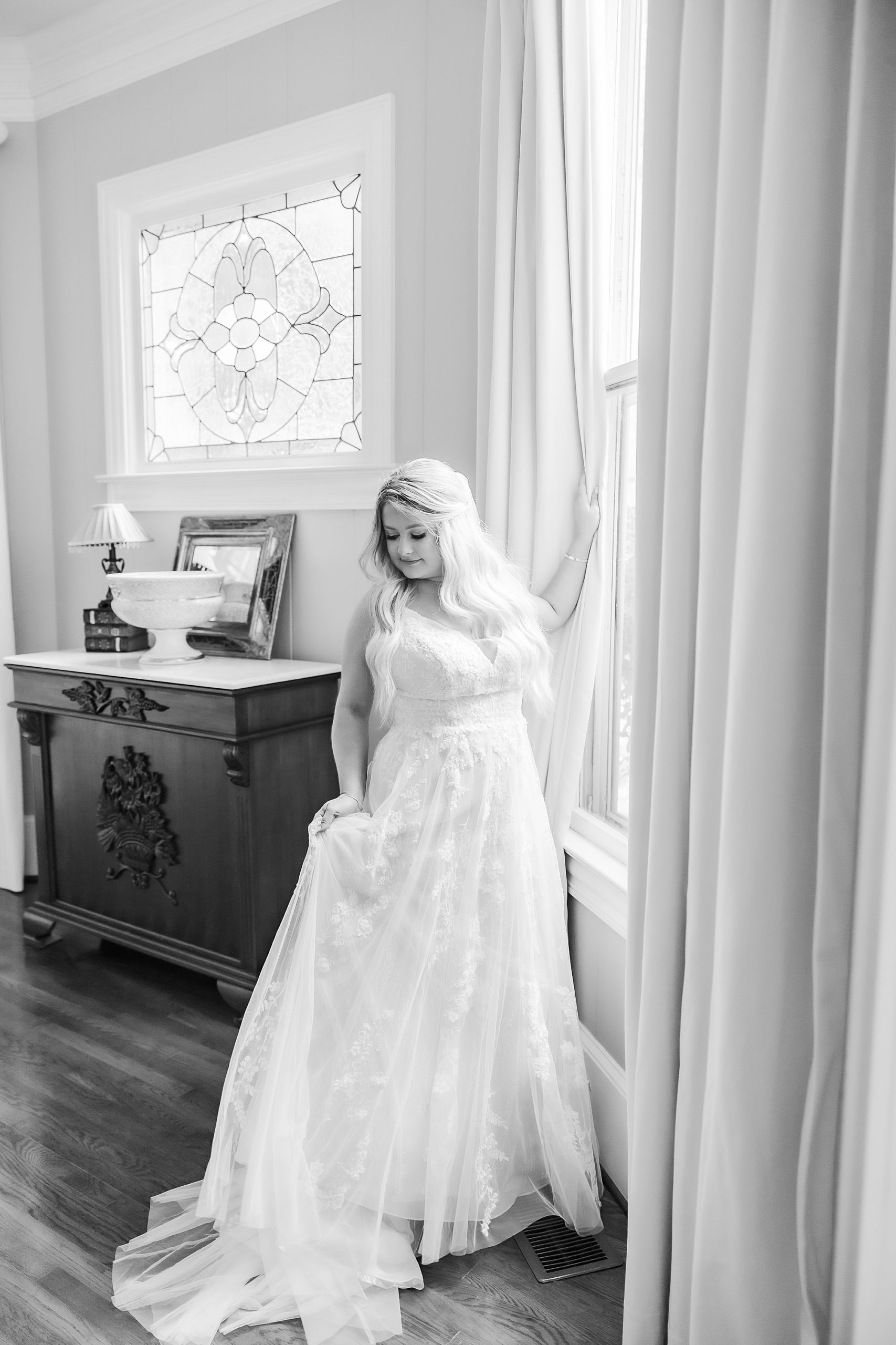 bride leans against a window looking over her shoulder