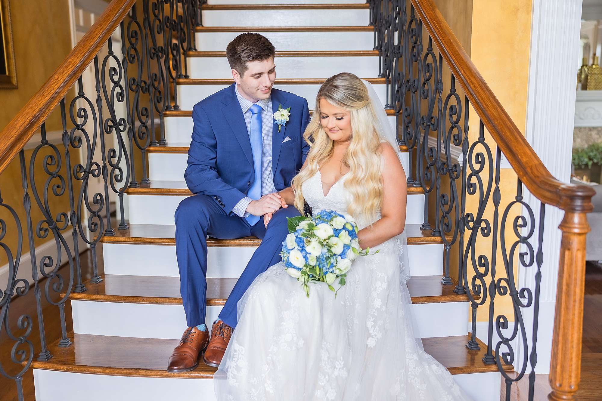 newlyweds sit on steps inside the Victoria Belle Mansion