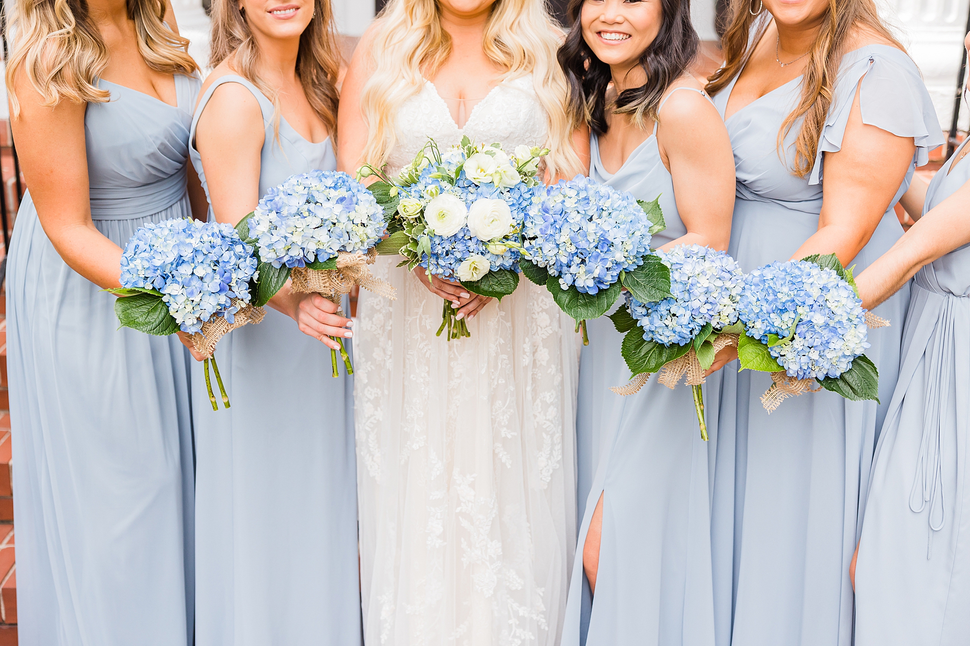 bridesmaids hold blue hydrangeas wearing light blue gown