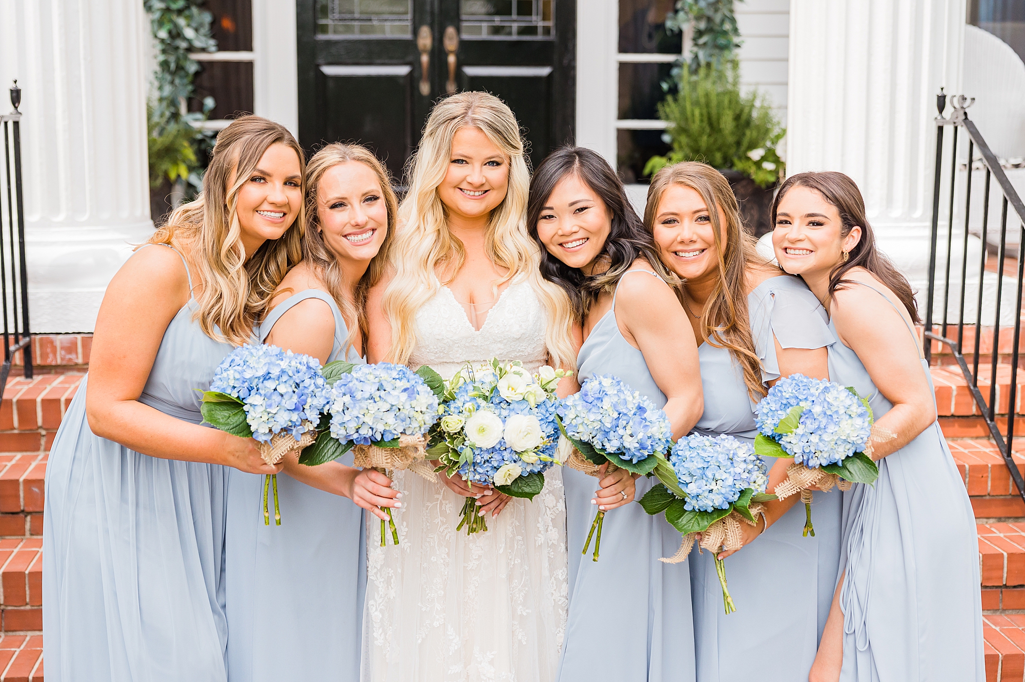 bridesmaids hug bride in light blue gowns