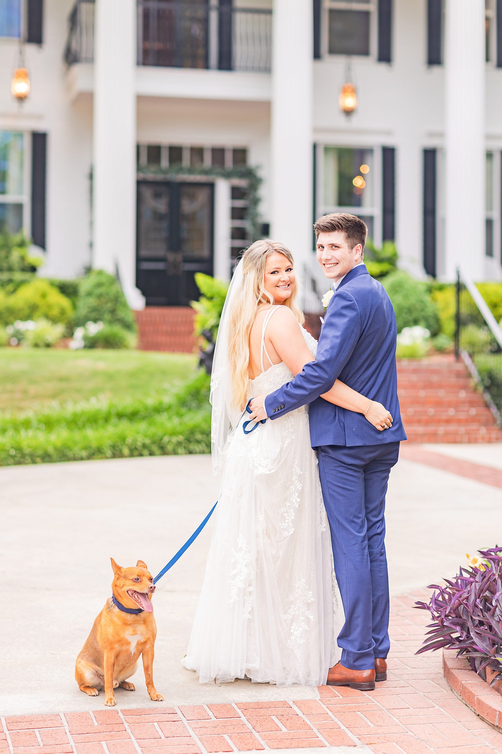 newlyweds stand with dog outside Georgia wedding venue