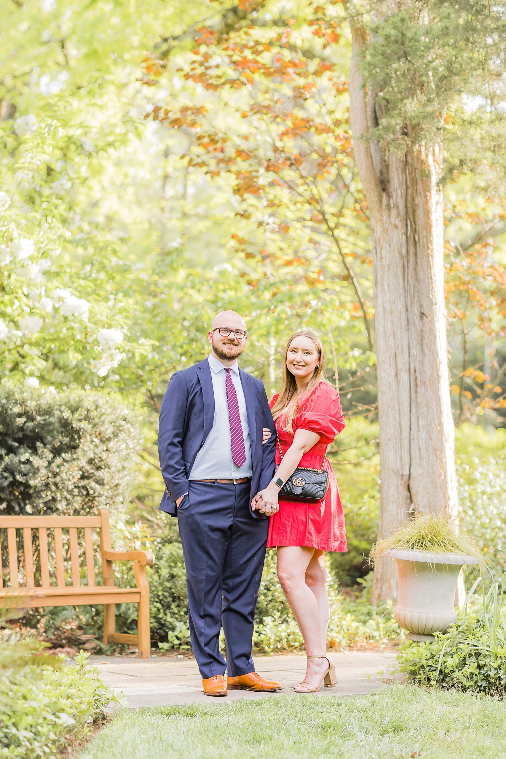 engaged couple stands together in Charlotte garden