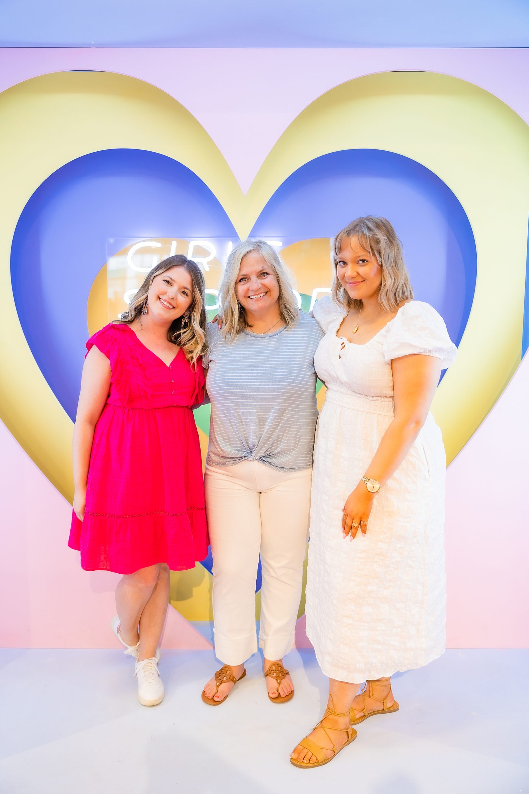 three owners of Girl Supply pose by large heart display
