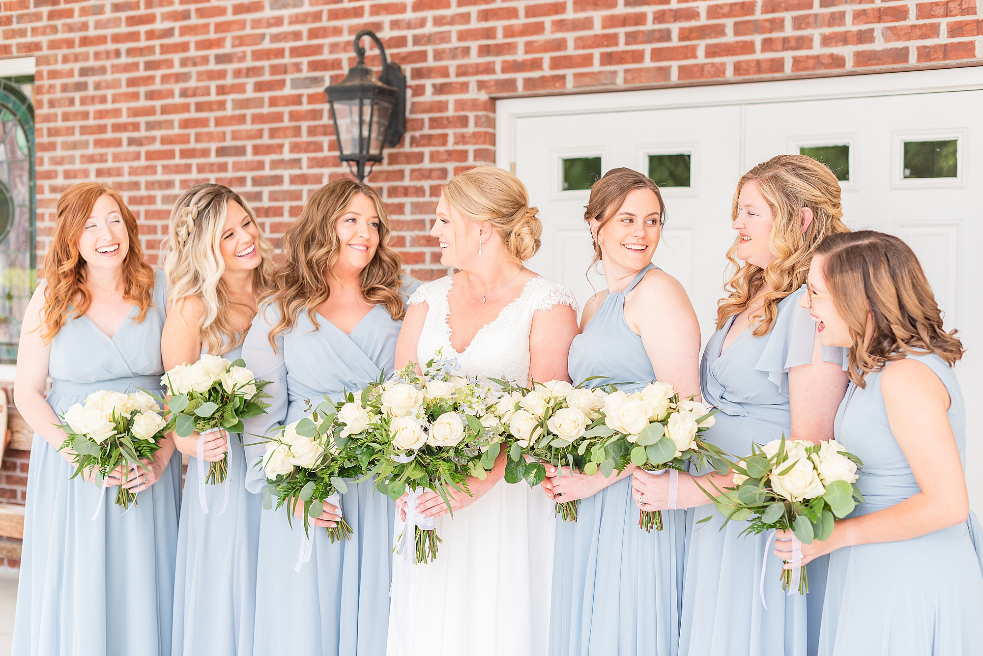 bride looks around at bridesmaids in light blue dresses