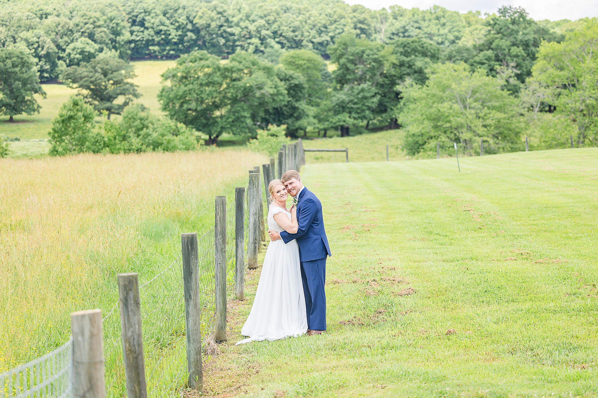 bride and groom lean heads together during Blairsville GA wedding portraits along fence