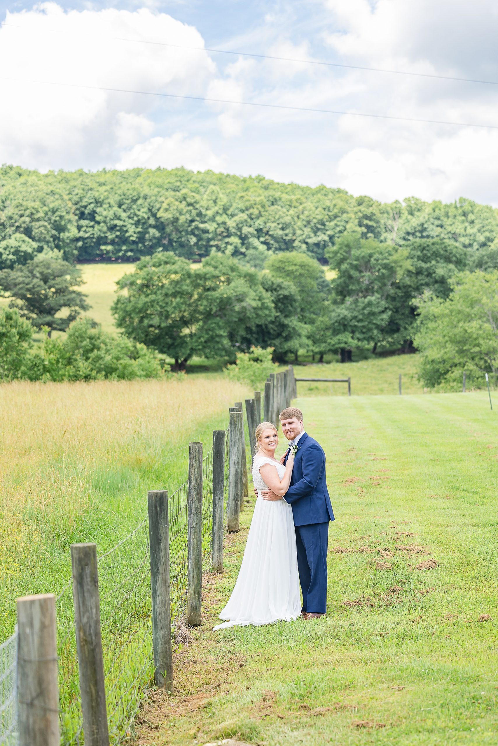bride and groom lean against fence line during Blairsville GA wedding photos