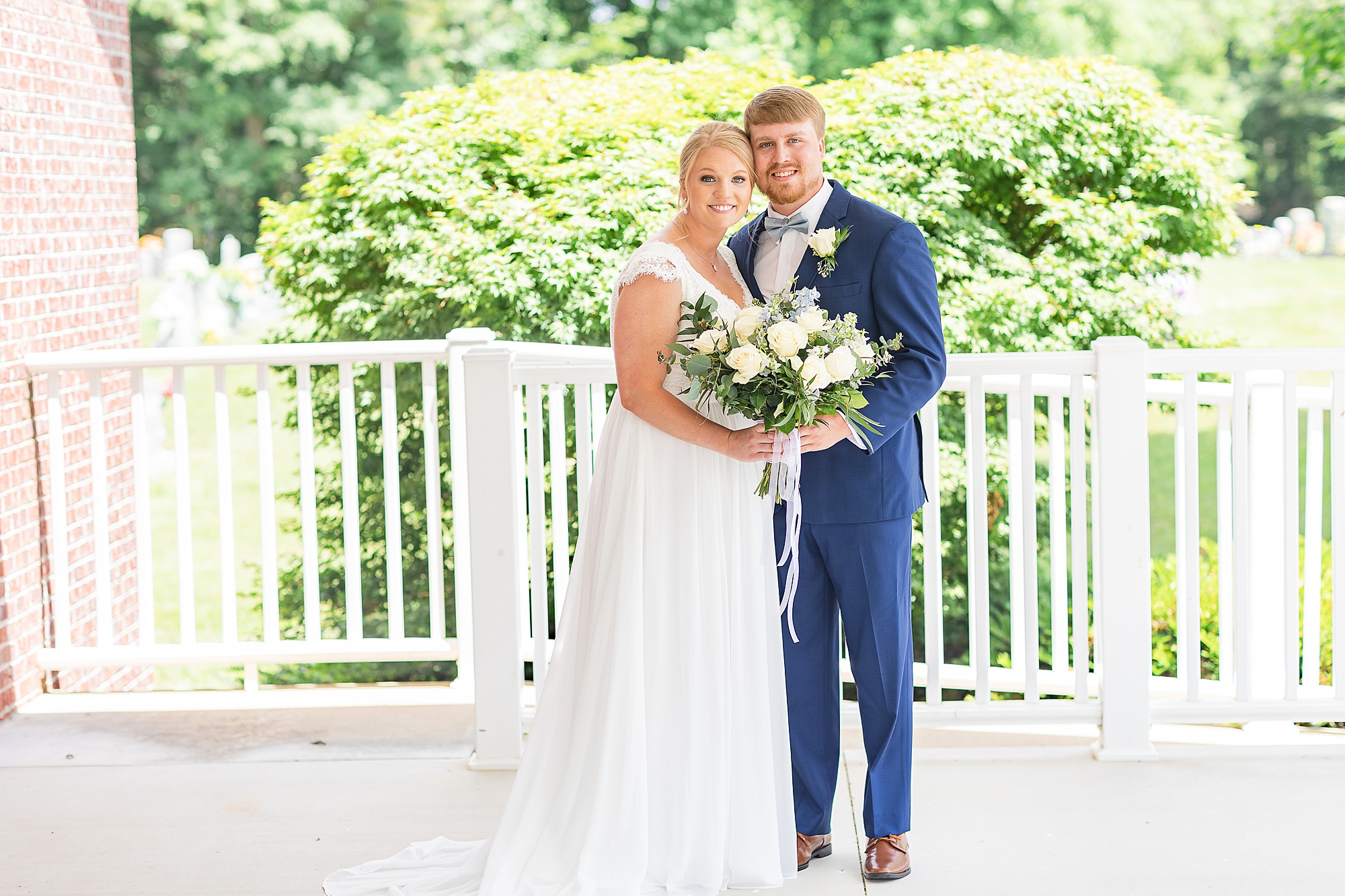 bride and groom stand together on white patio
