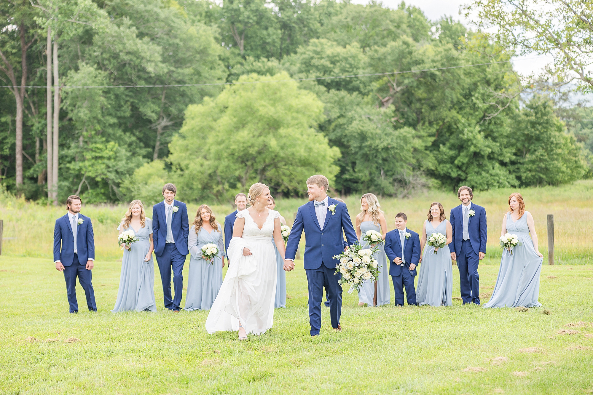 bride and groom hold hands walking through field during Blairsville GA wedding day
