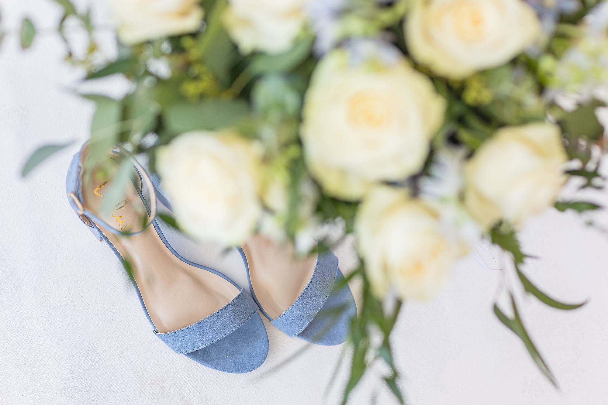 blue suede heels rest under yellow and blue bouquet