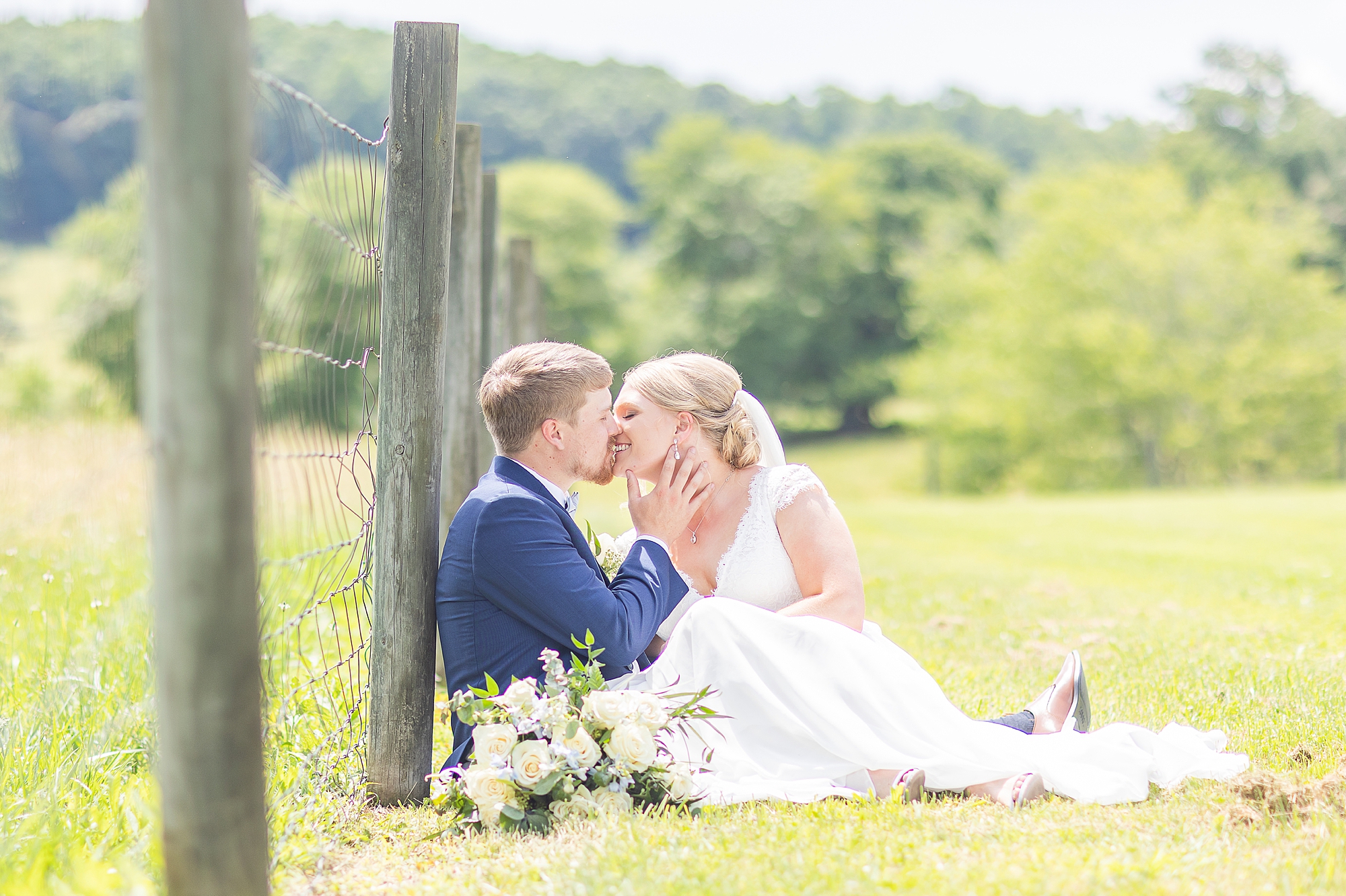 newlyweds kiss against wooden fence post