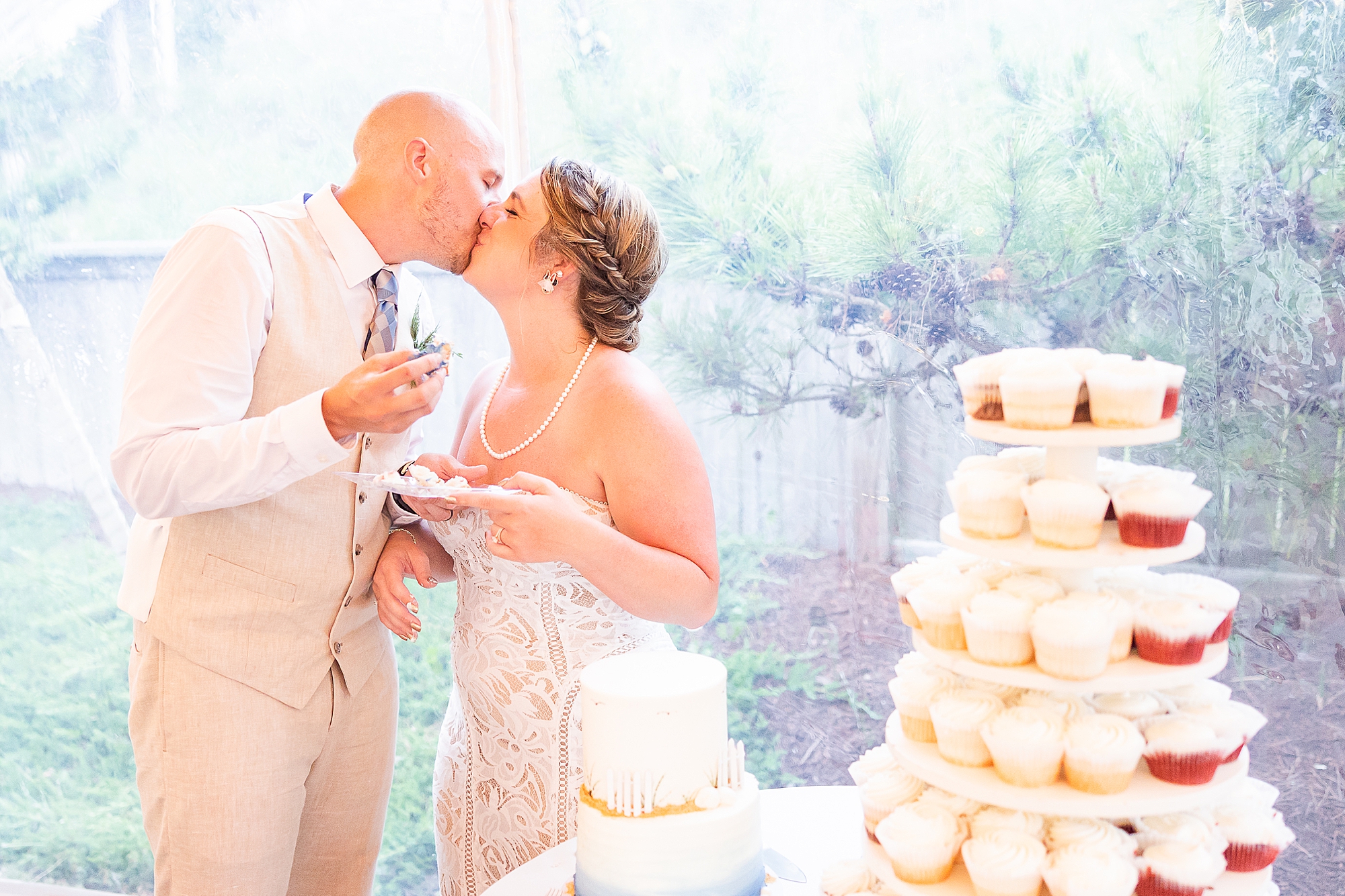 bride and groom kiss by display of cupcakes