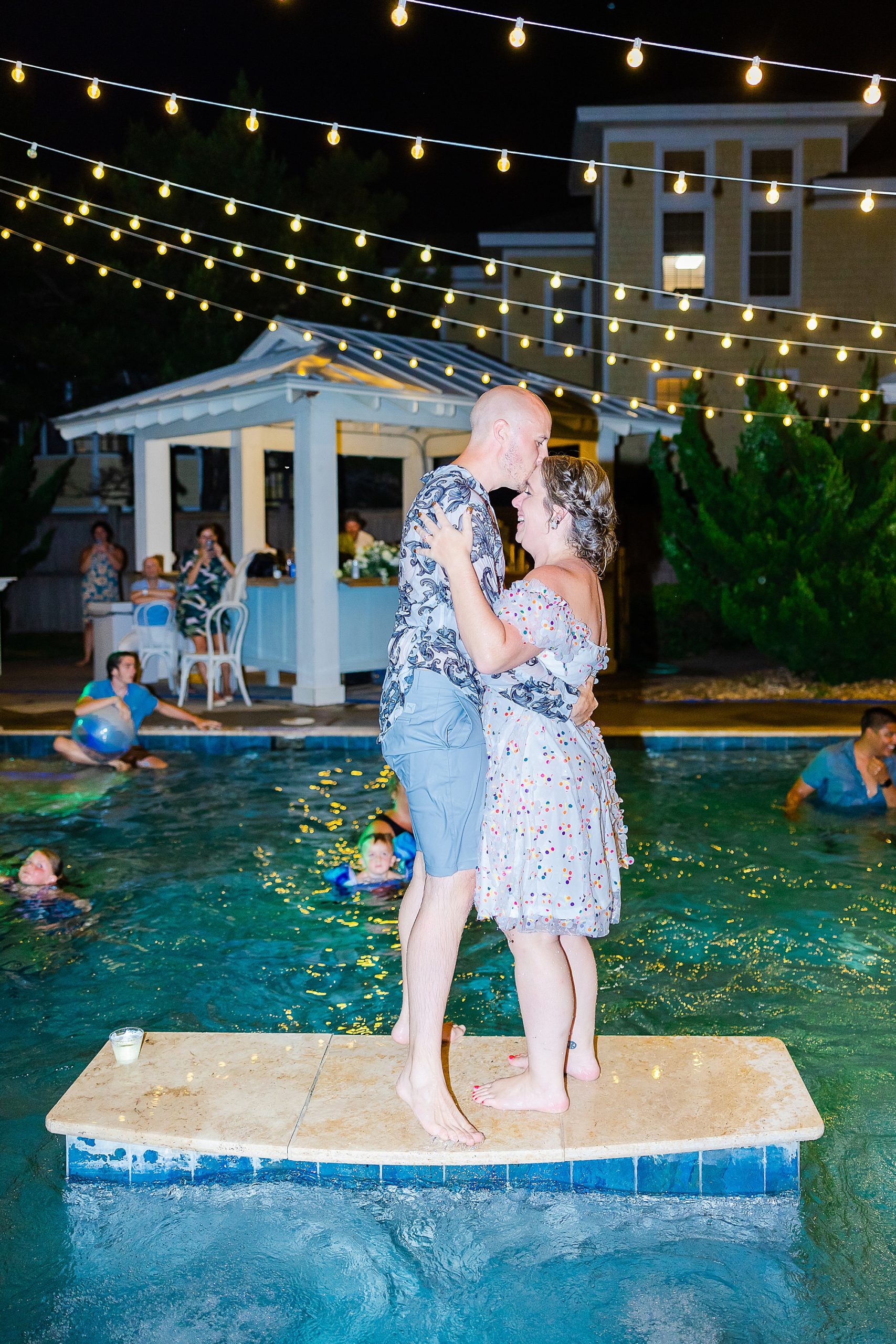 newlyweds stand on board in pool kissing