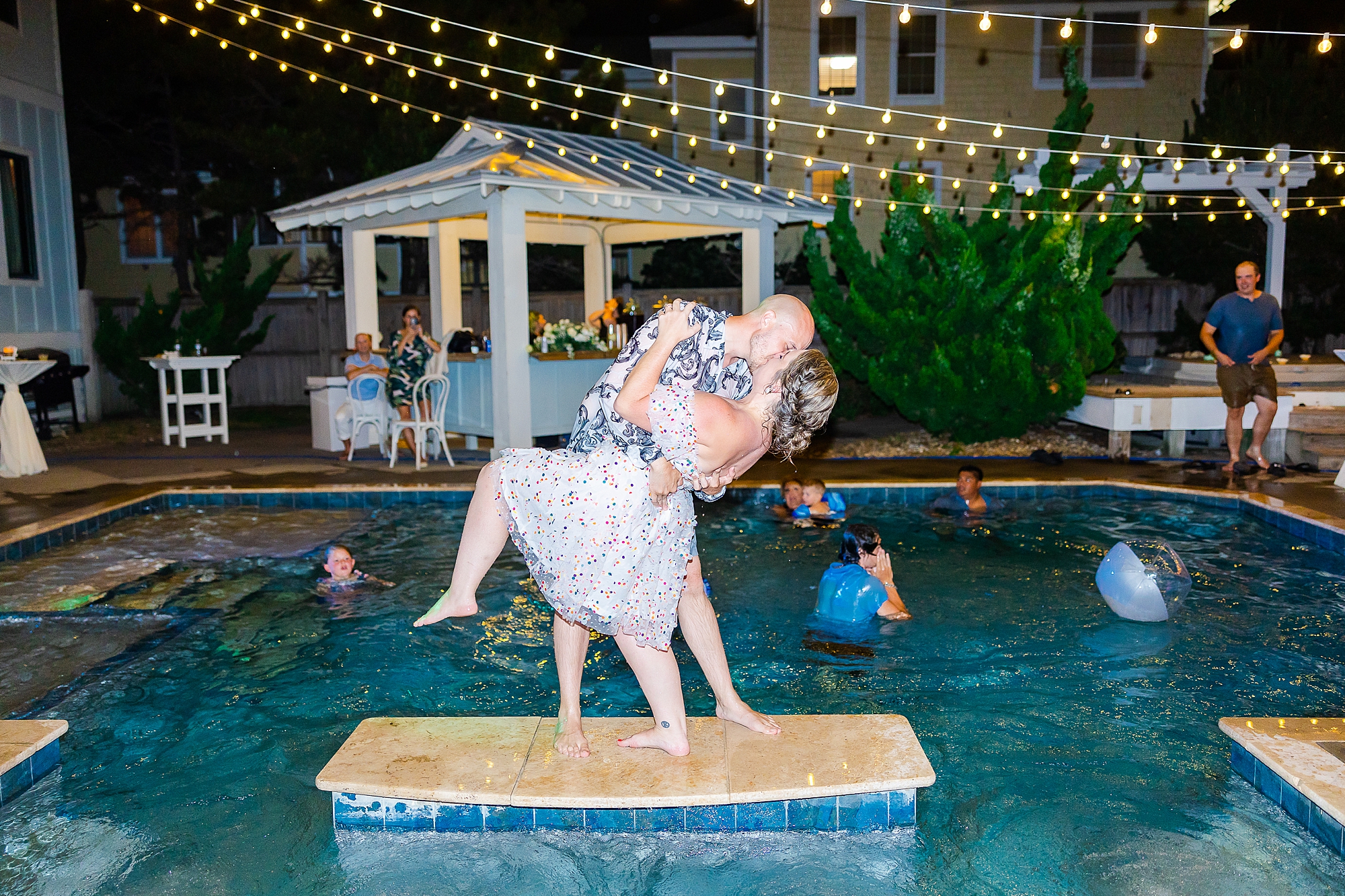 groom dips bride floating in pool