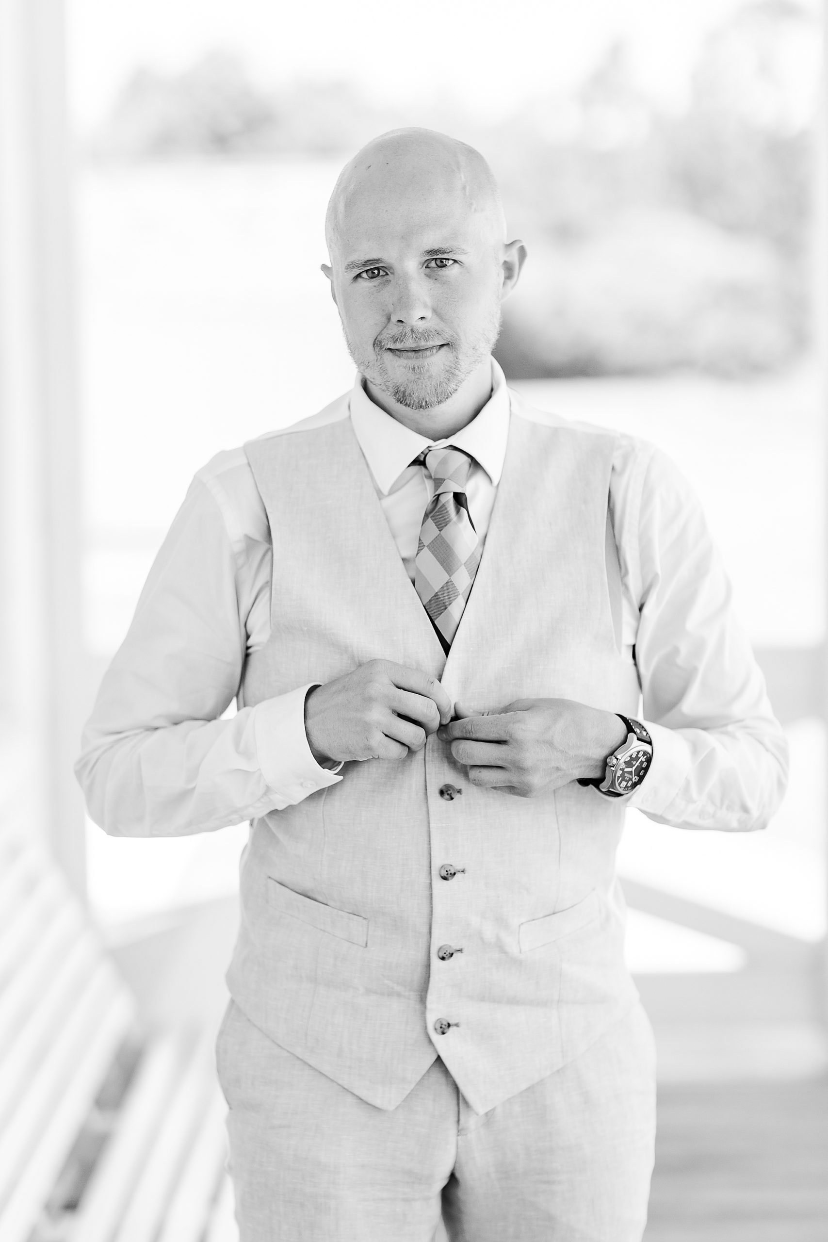 groom adjusts buttons on vest before OBX wedding