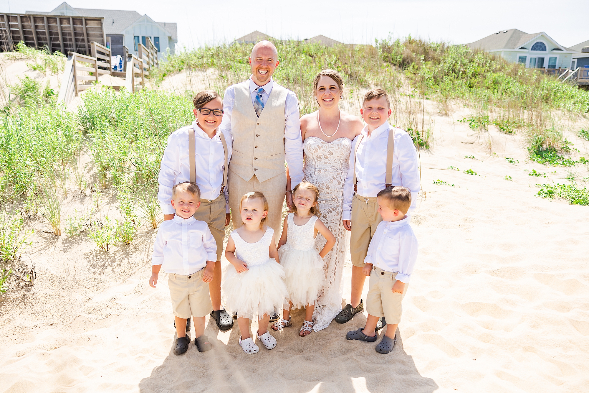 bride and groom pose with flower girls and ring bearers for beach wedding